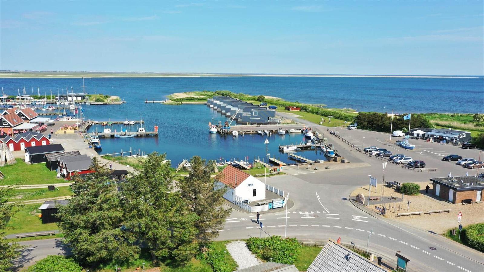 Hafen mit Krane, Booten und roten Häusern am Wasser.