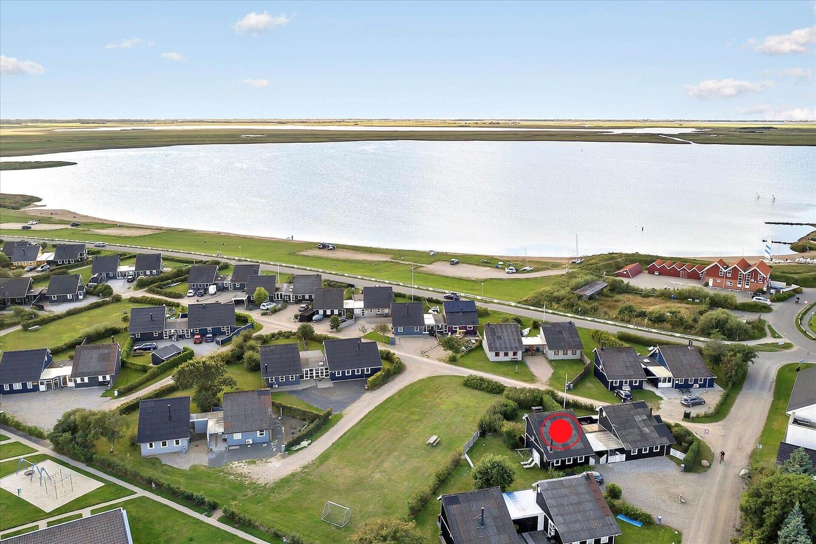 Kitesurfen am Strand mit mehreren Kites im Himmel und Personen im Wasser.
