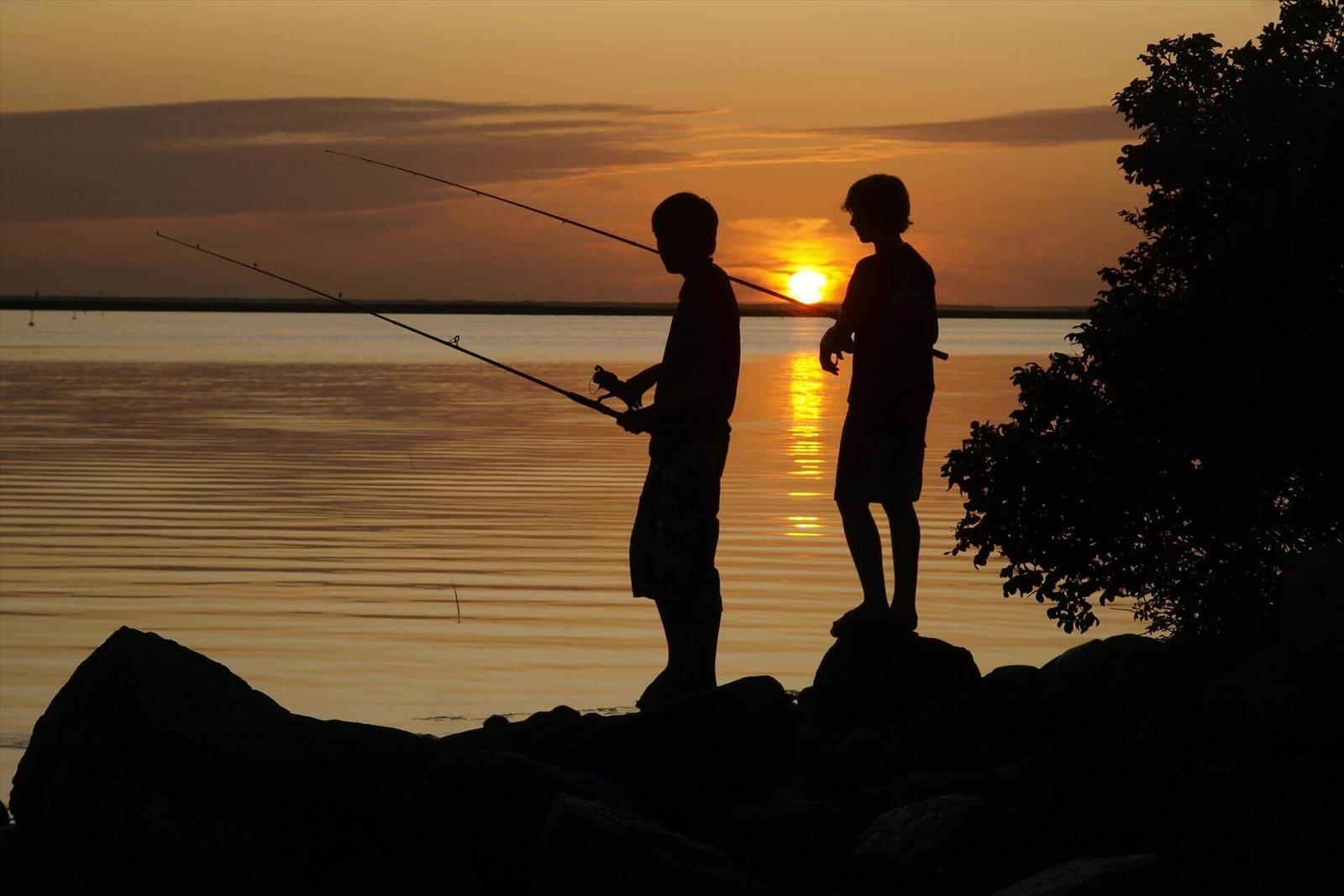 Sonnenuntergang über Hafen mit Booten und Kränen.