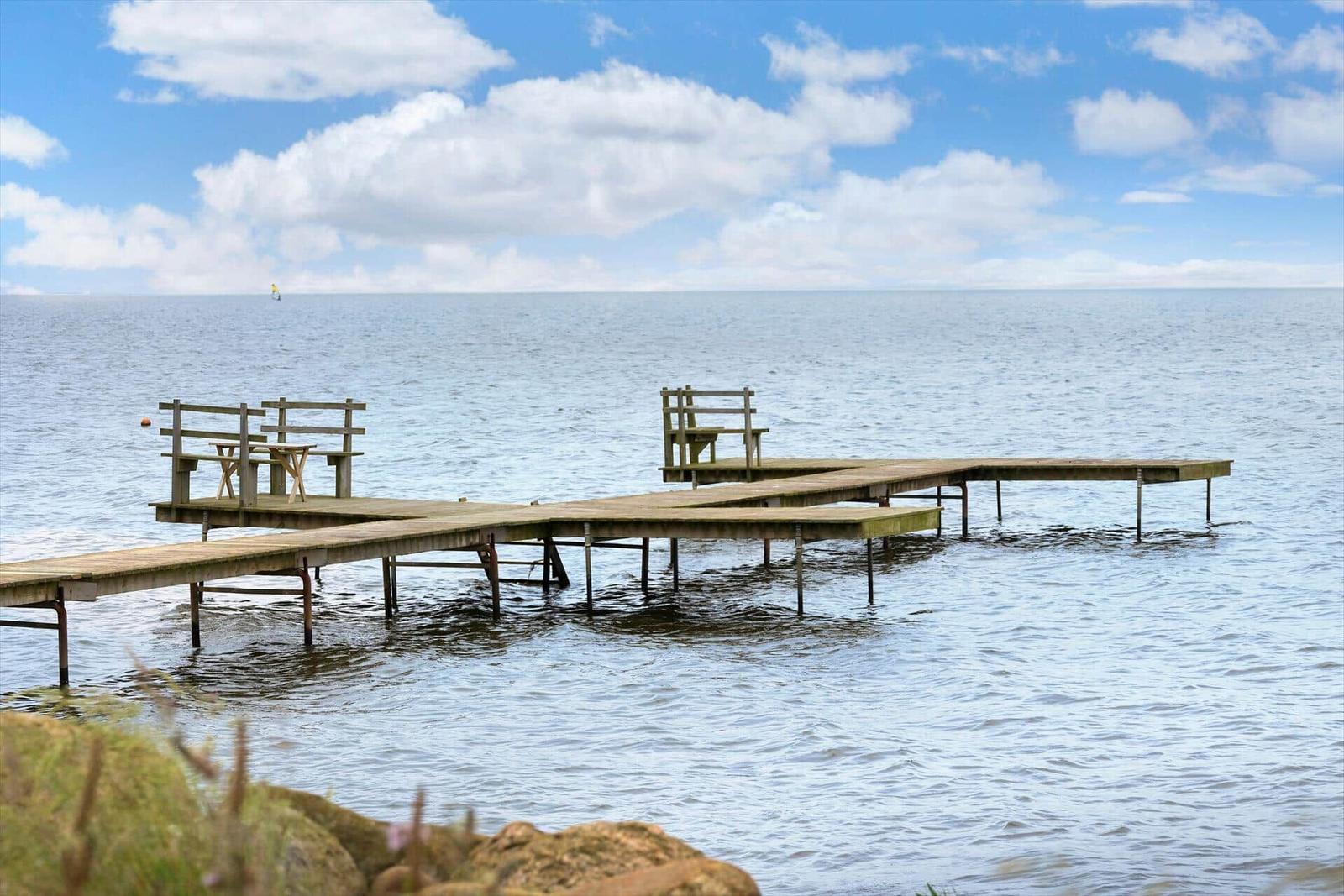 Windsurfer segeln auf dem Wasser, umgeben von Bäumen und Gras.