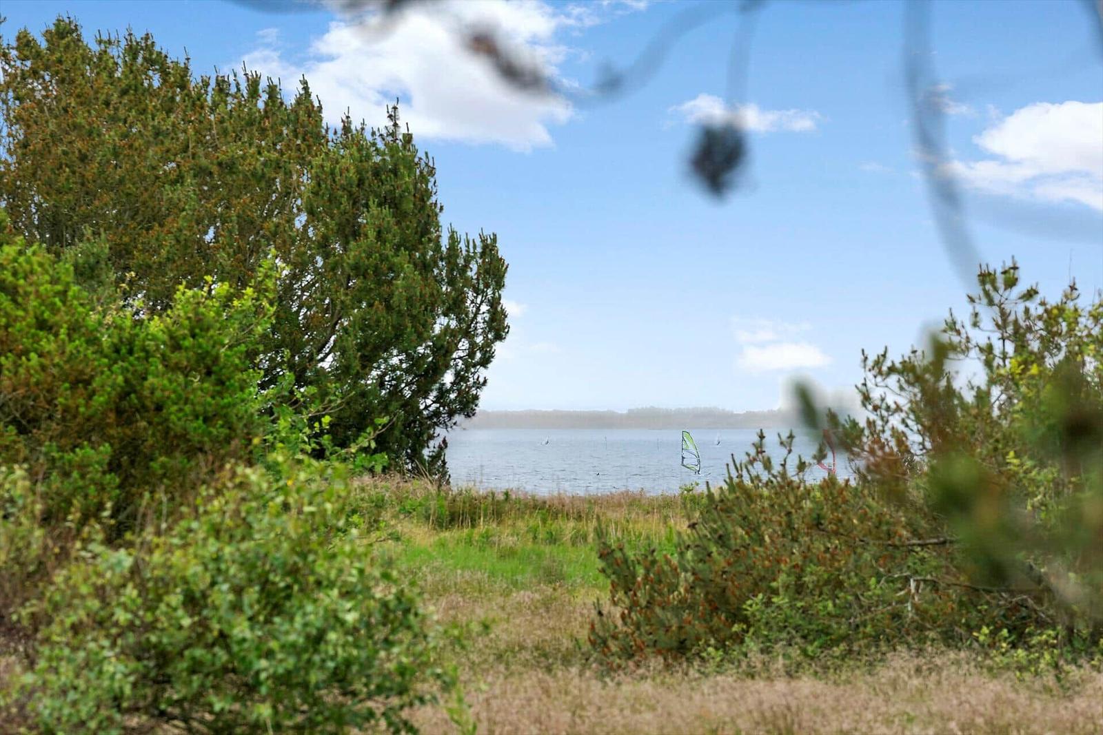 Grasfläche mit Picknicktisch am Strand, Blick auf das Meer unter blauem Himmel.
