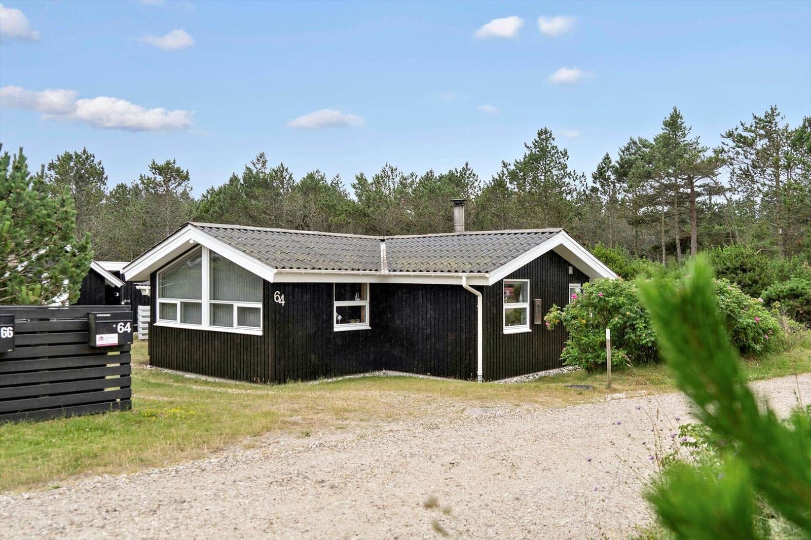 Schwarze Holzhütte mit Grill und weißem Tor im Garten.