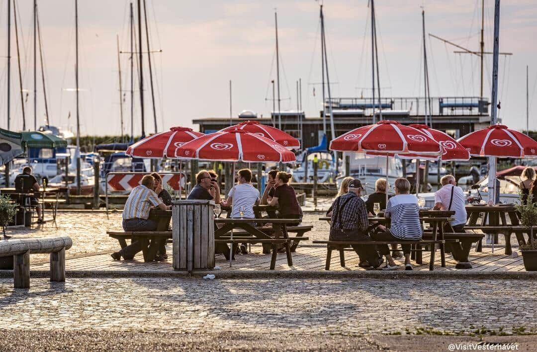 Hafen mit Booten und Steg im Vordergrund. Spiegelglatter See und klare Luft.