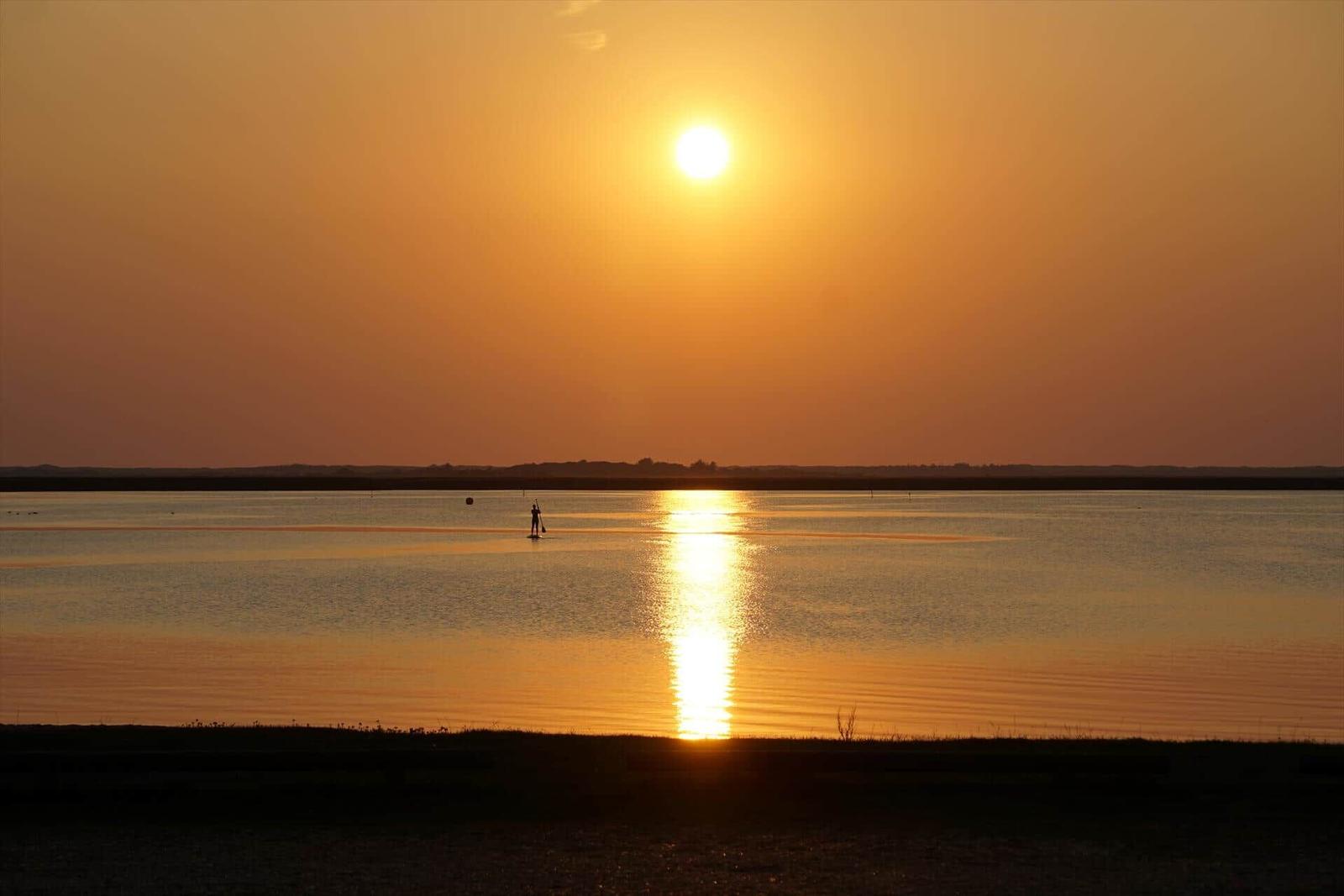 Ein Paar sitzt am Hafen und isst Eis während Sonnenuntergang.