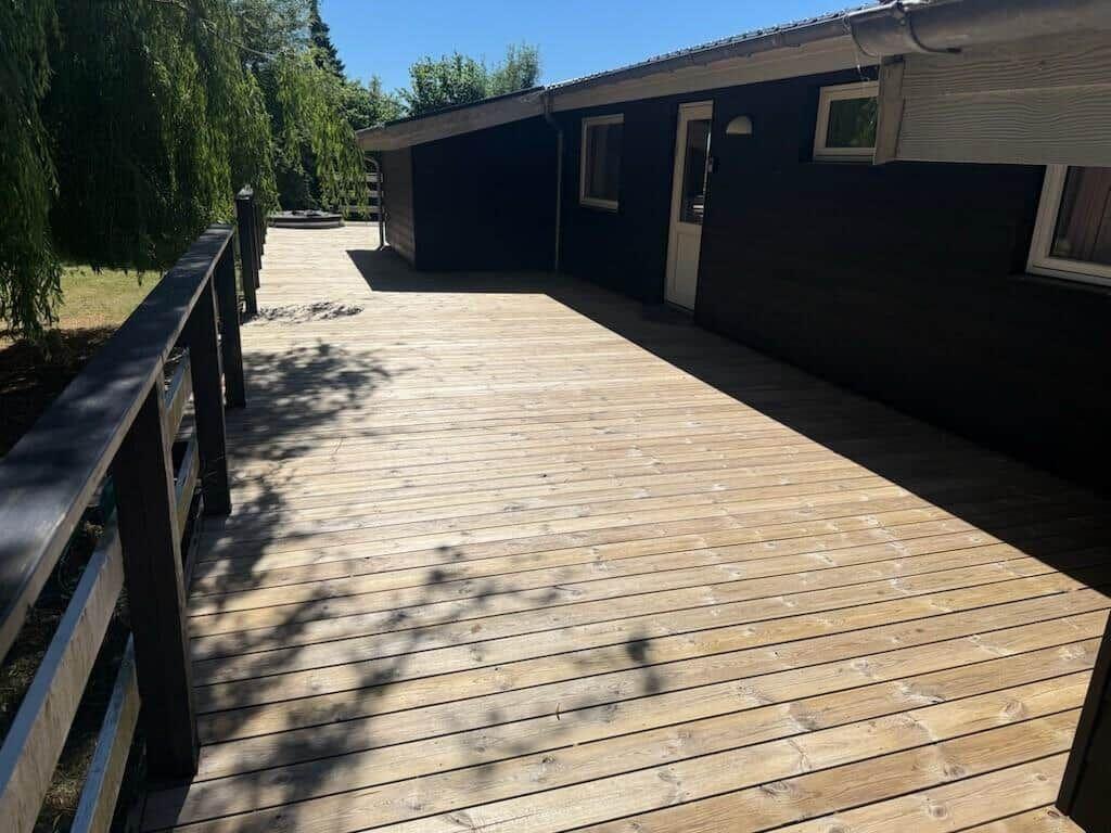Holzterrasse mit Geländer und Blick auf das Haus.