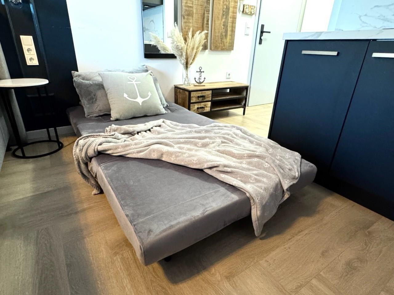 Schlafzimmer mit Bett, Kissen und Decke. Holzfußboden und dunkler Schrank.