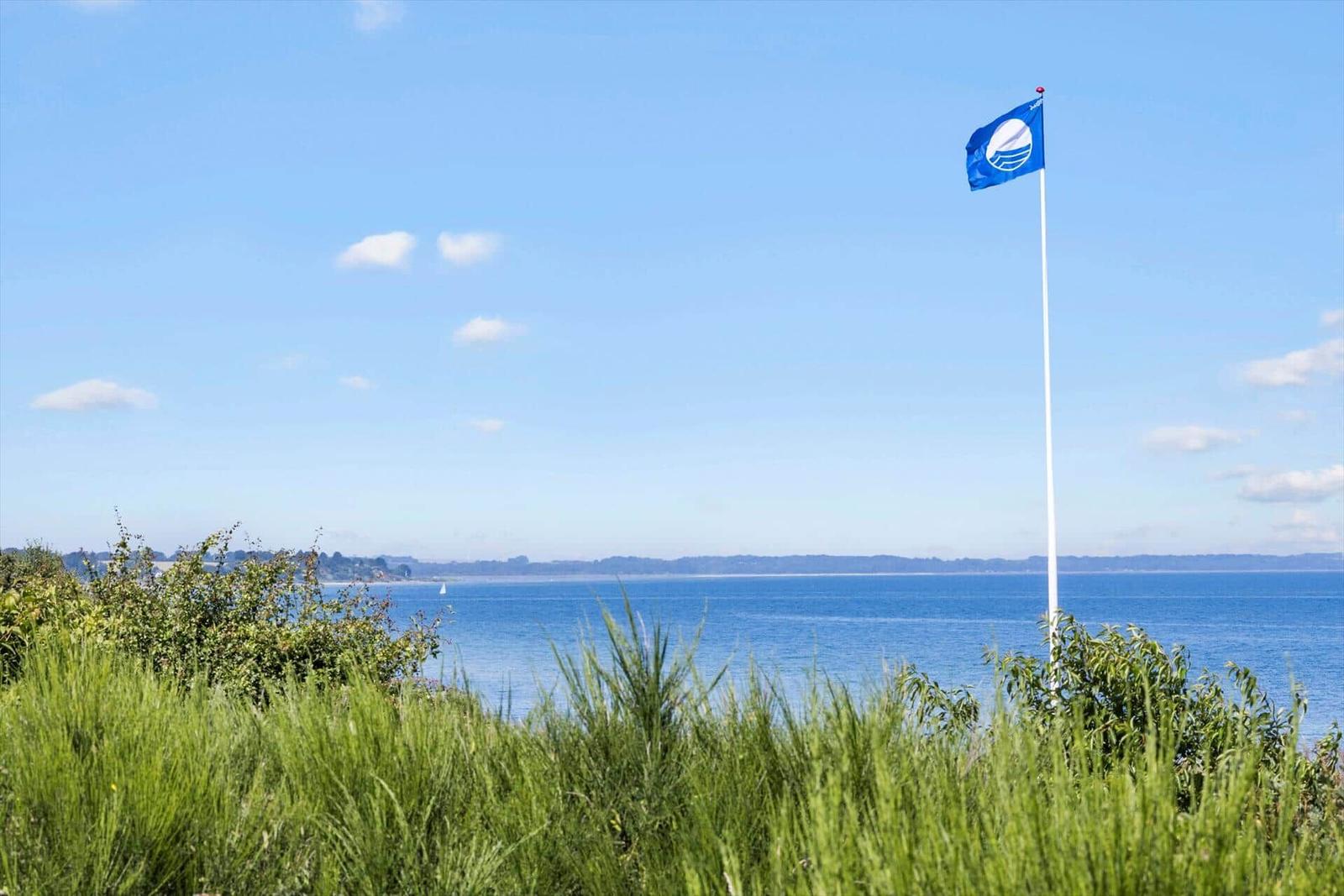 Grasland am Strand mit Blick auf das Meer und Häuser in der Ferne.