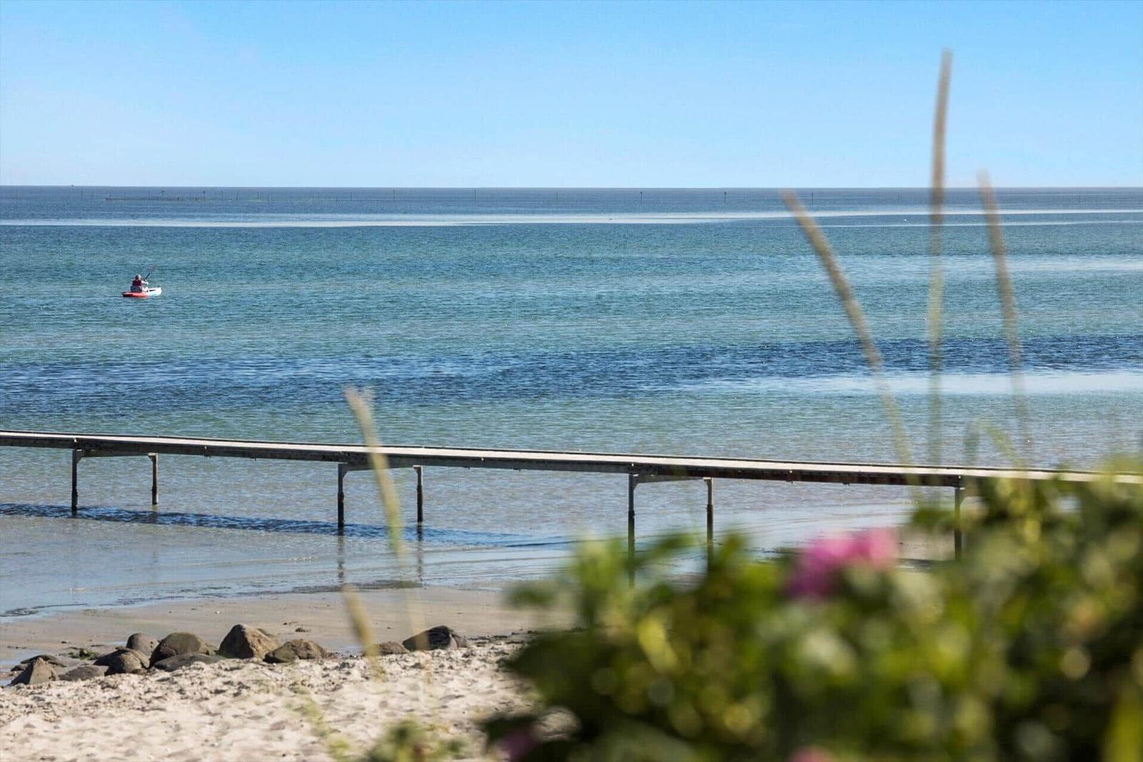 Rotes Haus mit Eiscreme-Skulpturen am Strand. Außenterrasse mit Sonnenschirmen und Blick aufs Meer.