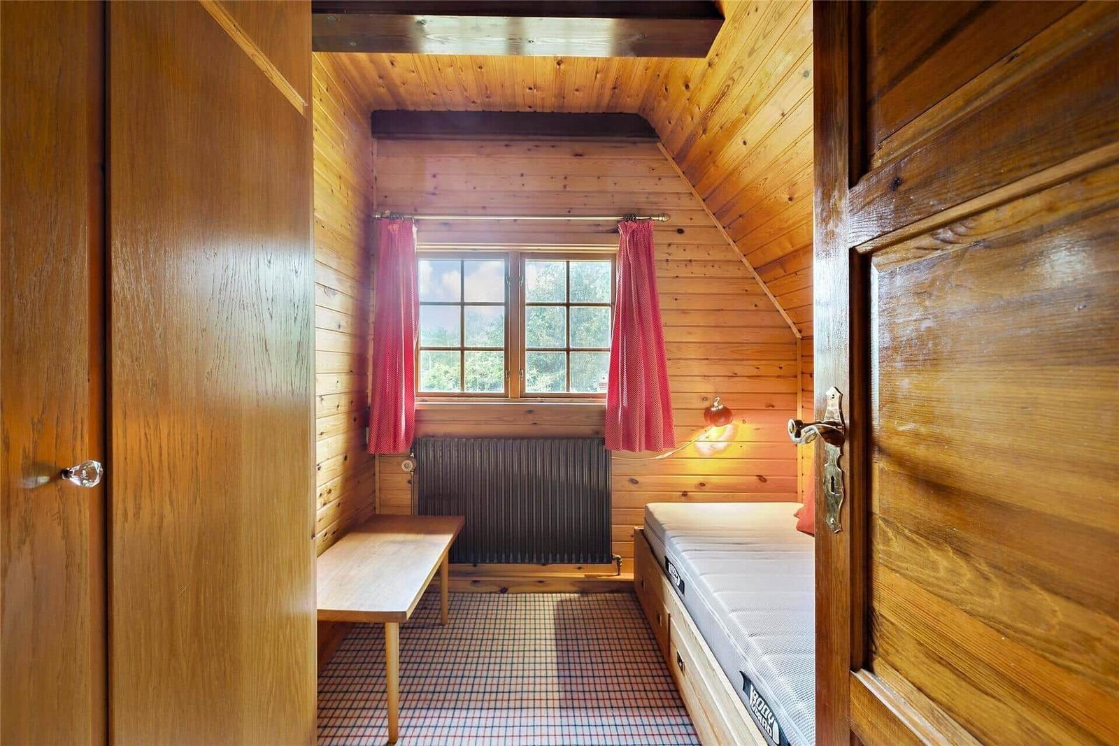 Haus mit Strohdach, gelber Fassade und Bäumen im Vorgarten.