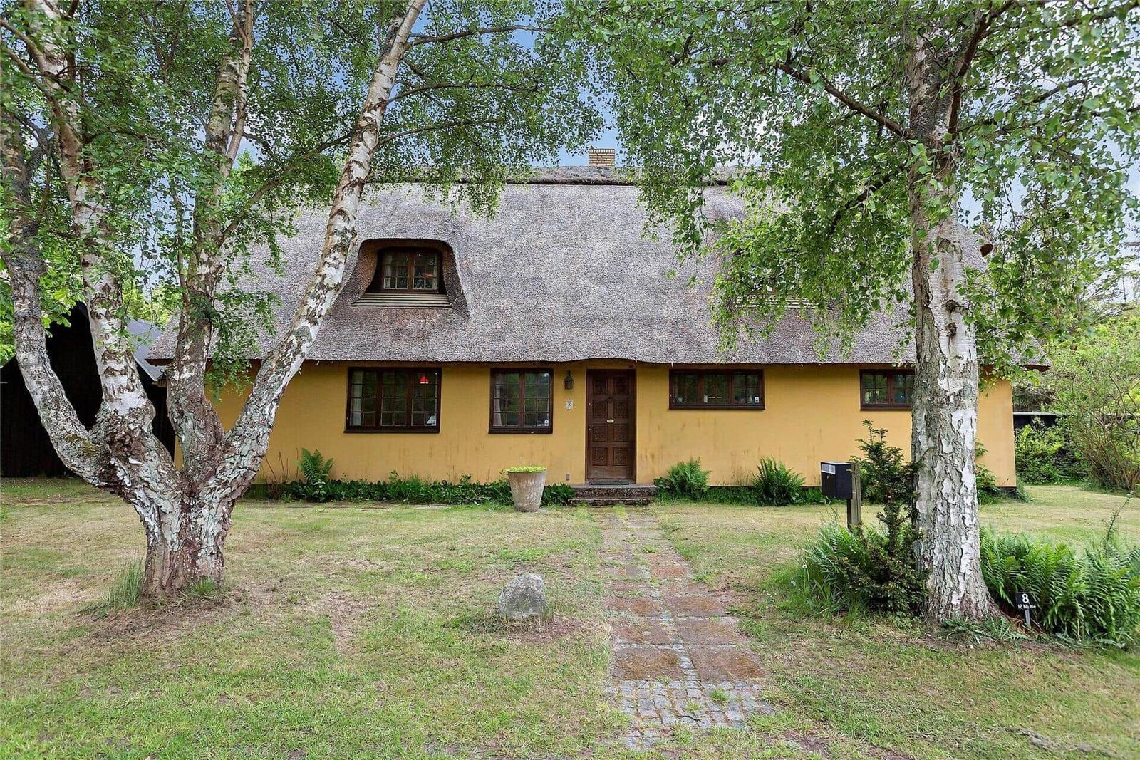Haus mit Strohdach, großer Garten und Kinderspielplatz mit Schaukel.
