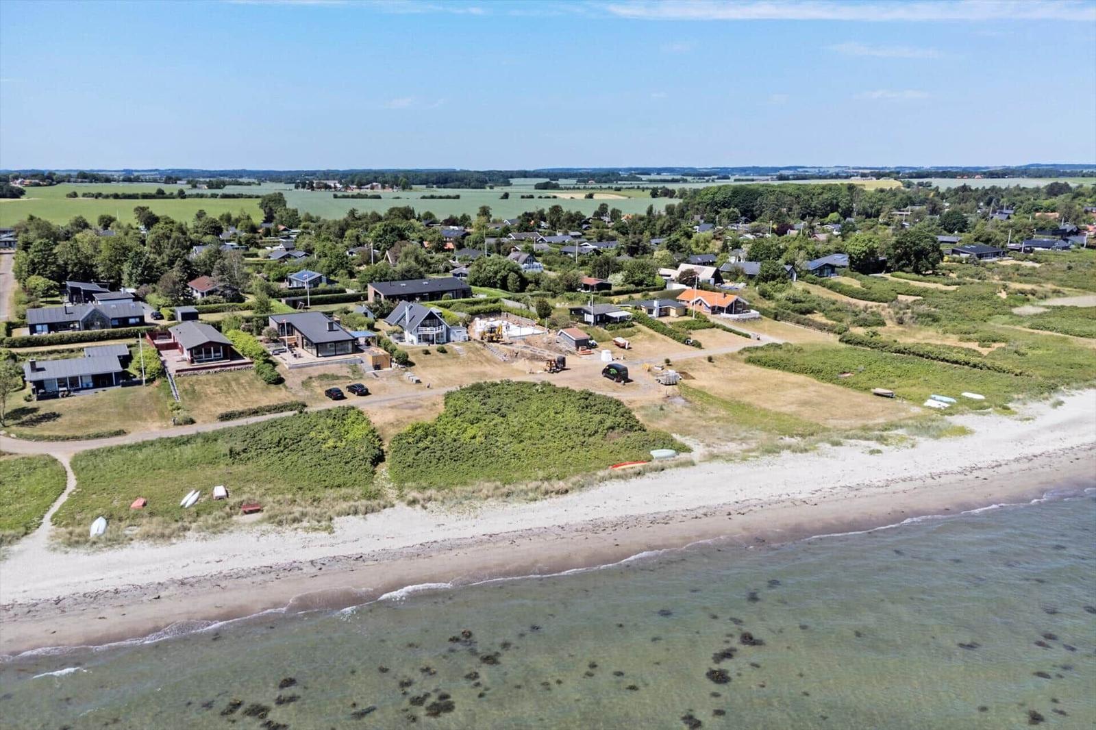 Strand mit Strohhut, Handtuch und Sandalen. Blick auf das Meer mit Segelboot.