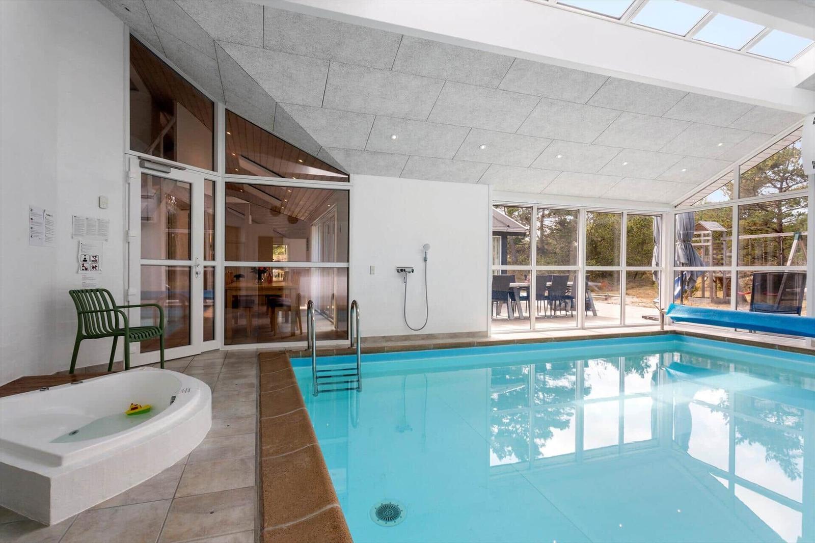 Innenpool mit rechteckigem Becken, Whirlpool, Glasfront und Oberlicht.