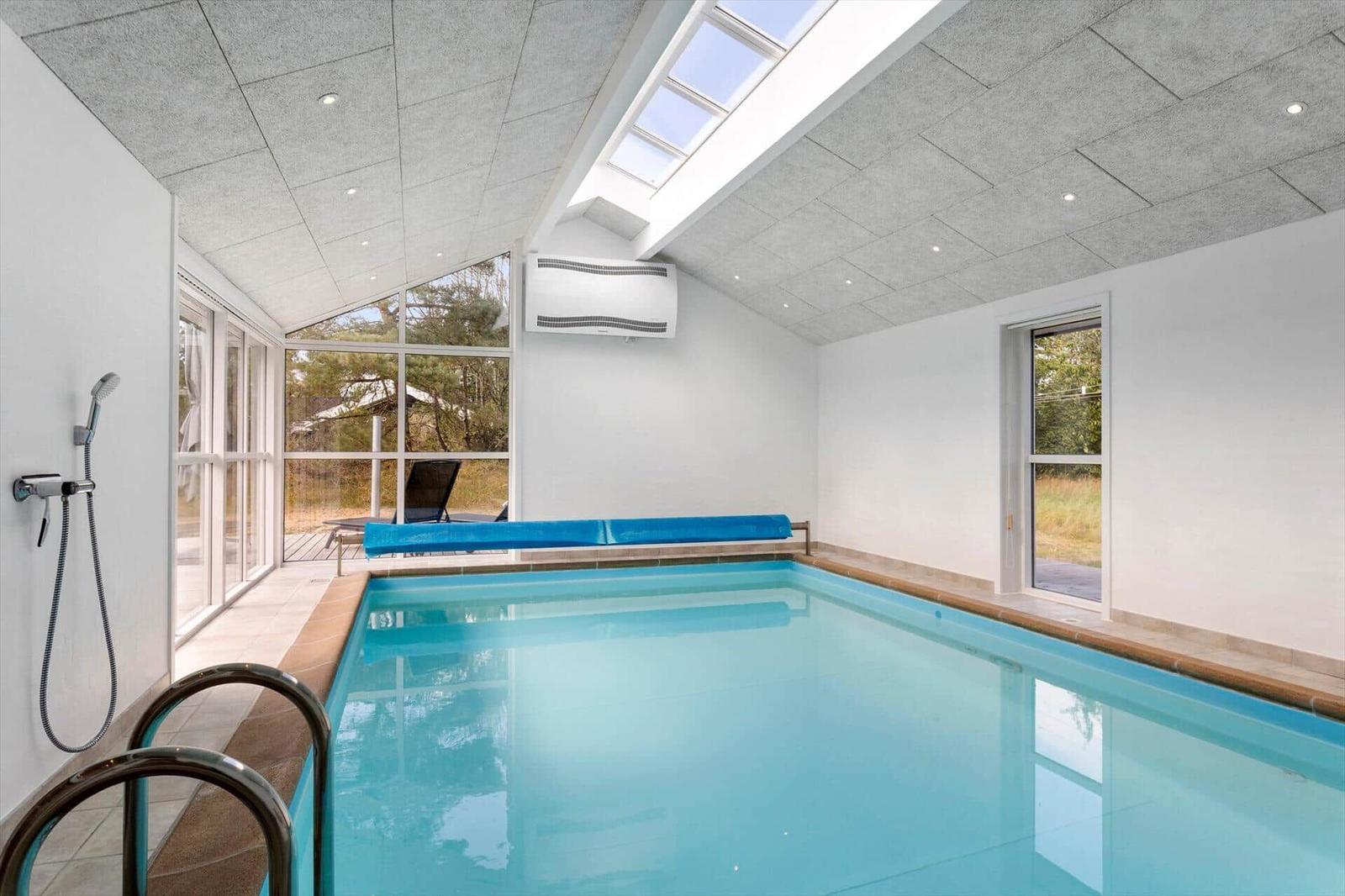 Innenpool mit türkisem Wasser, Oberlicht, Fensterfront und gerollter Abdeckung.