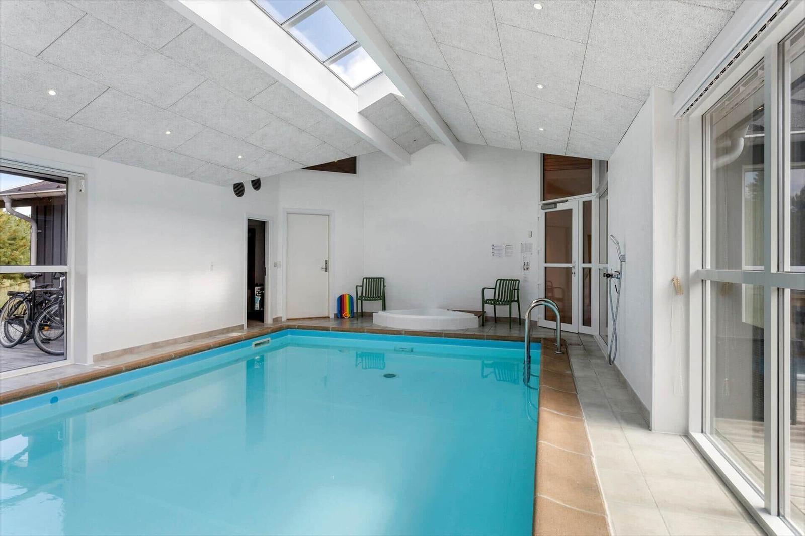 Innenpool mit türkisem Wasser, rundem Whirlpool, Oberlicht und Fensterfront.