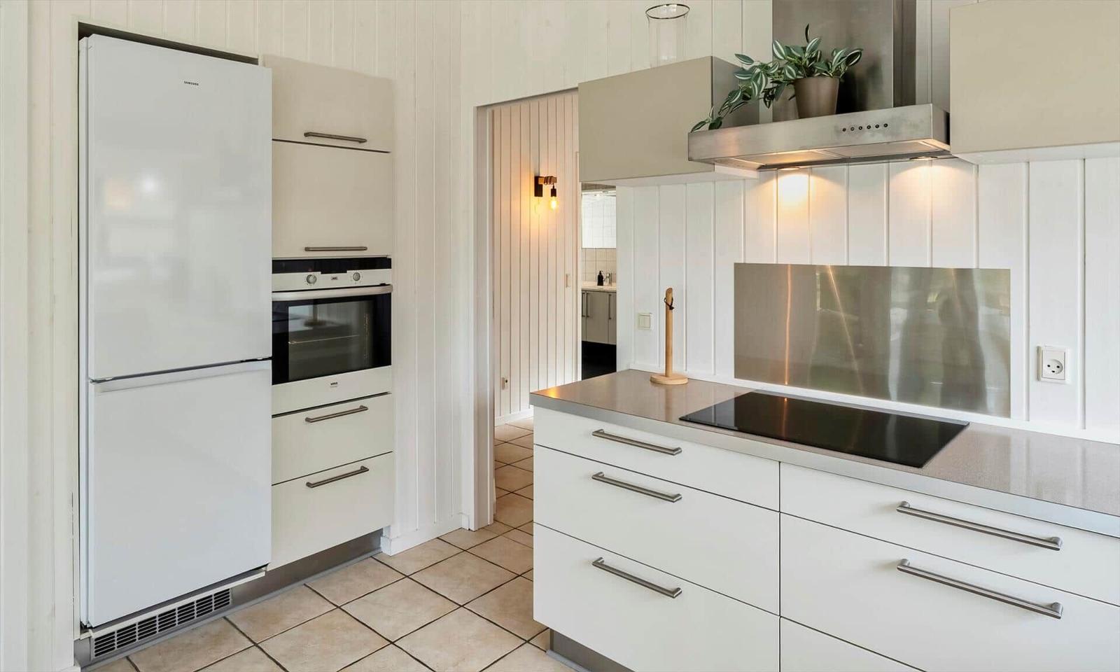Küche mit Kühlschrank, Backofen, Ceranfeld und Edelstahl-Dunstabzug.