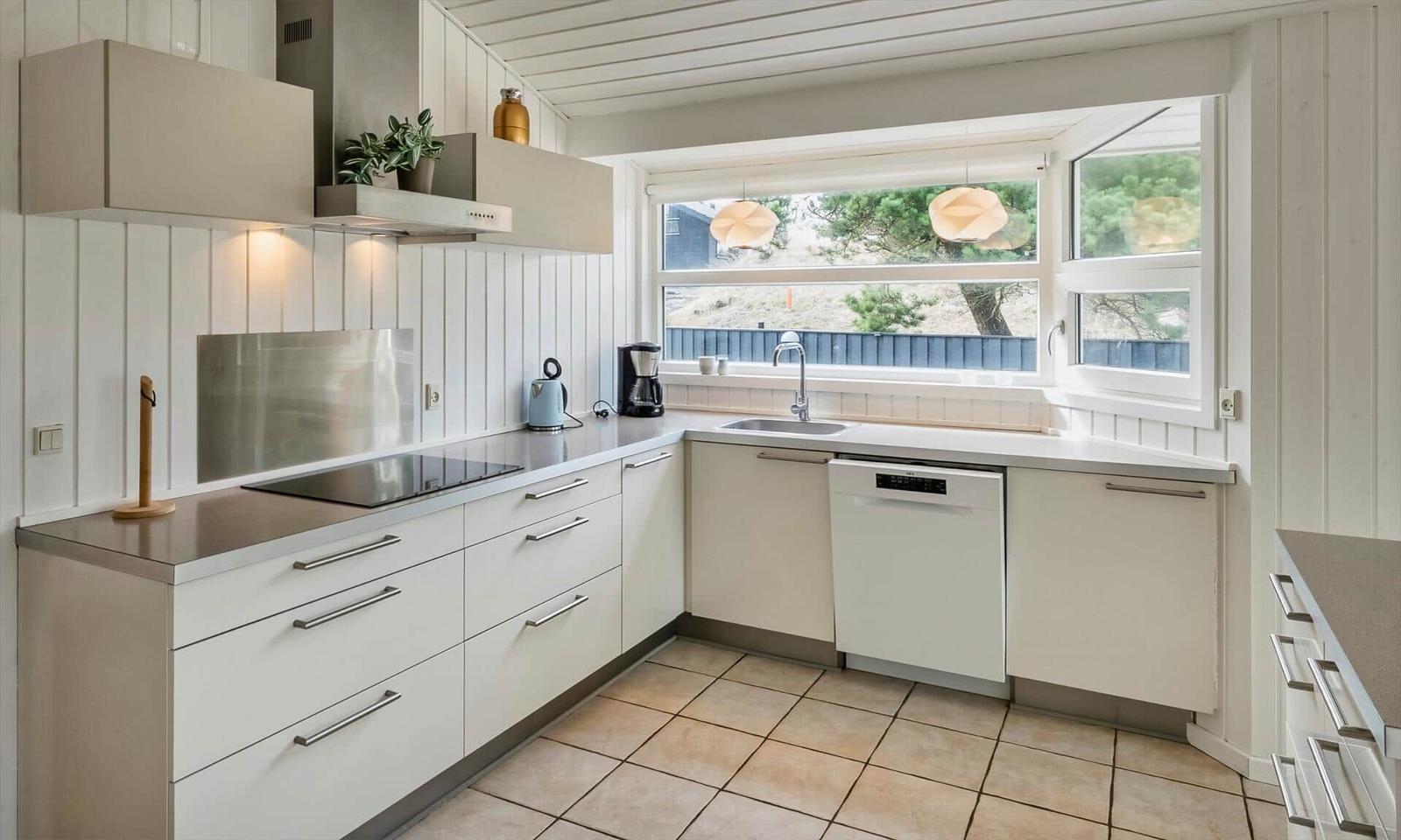L-Küche mit Ceranfeld, Spüle am Fenster, Geschirrspüler und Dunstabzug.