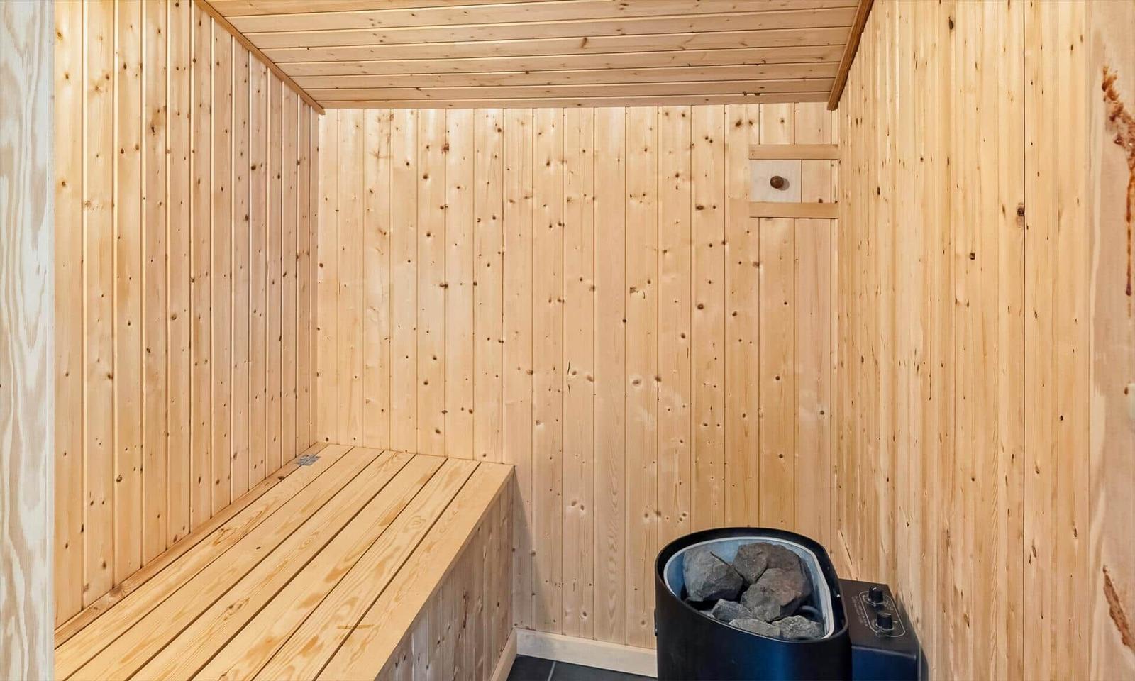 Sauna mit heller Holzverkleidung, Lattenbank und schwarzem Elektroofen.