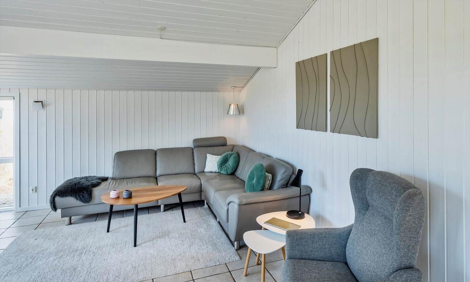 Wohnbereich mit grauem Ledersofa, Holzcouchtisch und grauem Sessel.