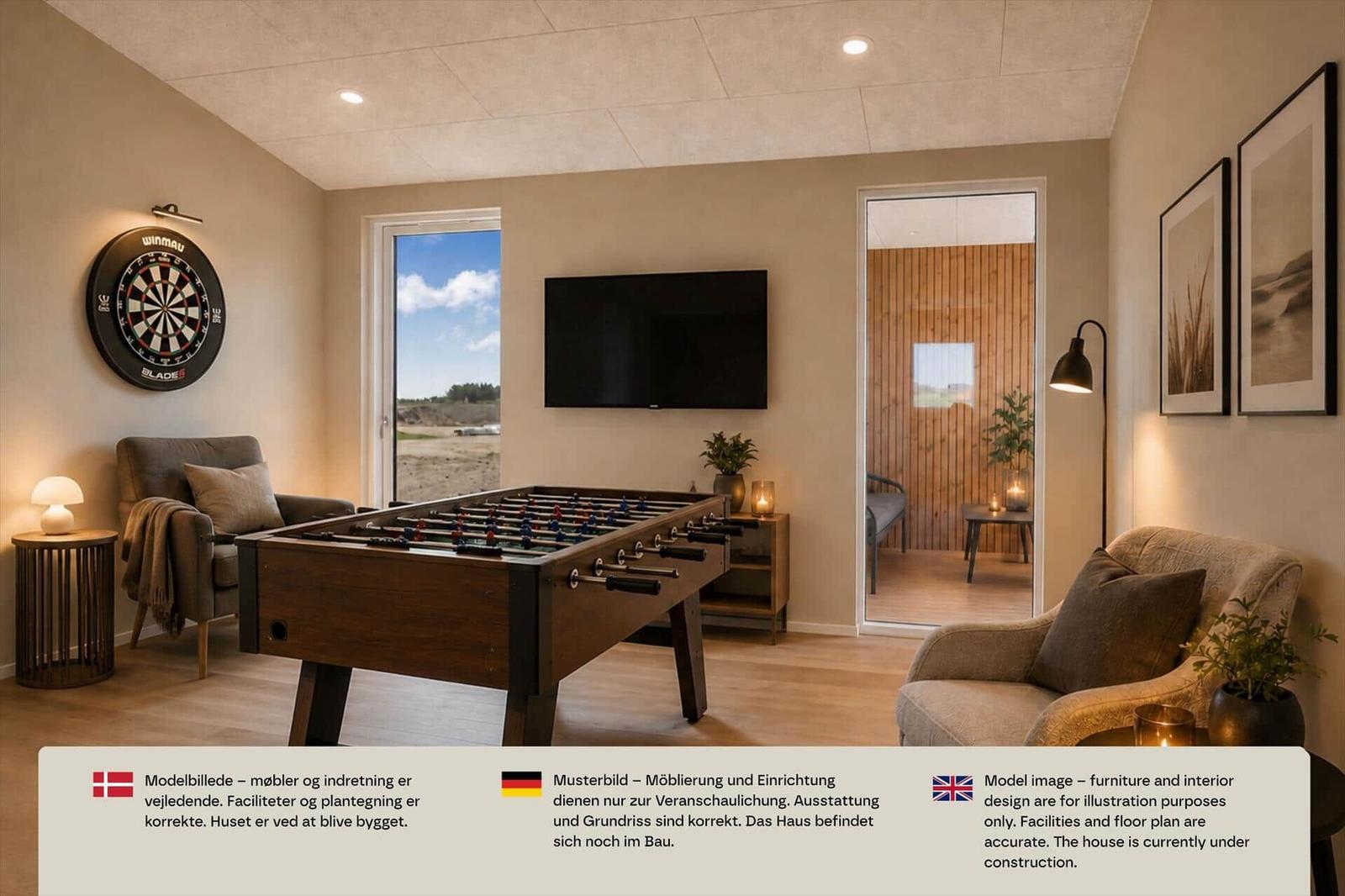 Spielzimmer mit Kicker, Dartscheibe, Wandfernseher und zwei Sesseln auf Holzboden.