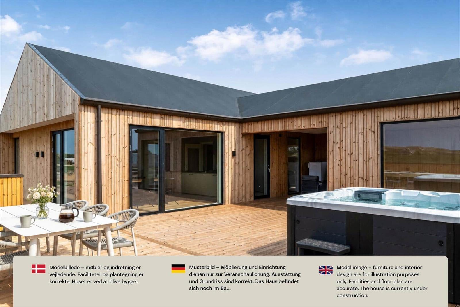 Helles L-förmiges Holzhaus mit Terrasse, Esstisch und Whirlpool unter blauem Himmel.