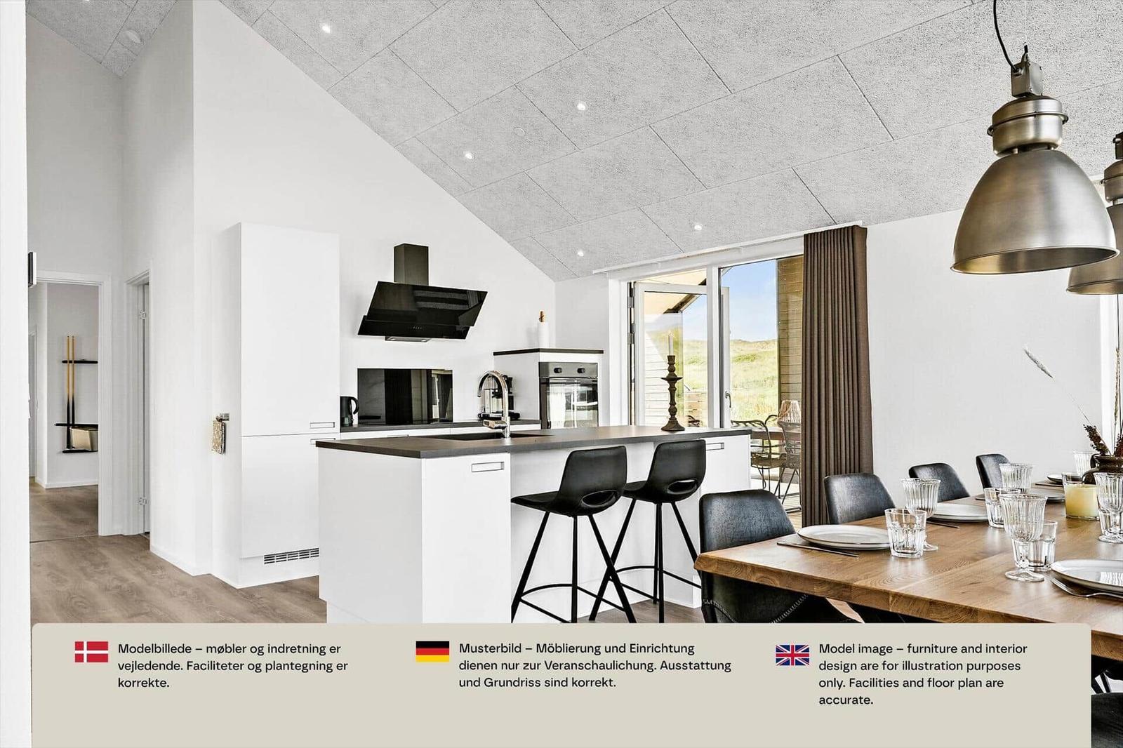 Offene Küche mit weißer Insel, zwei Barhockern und Esstisch mit schwarzen Stühlen.