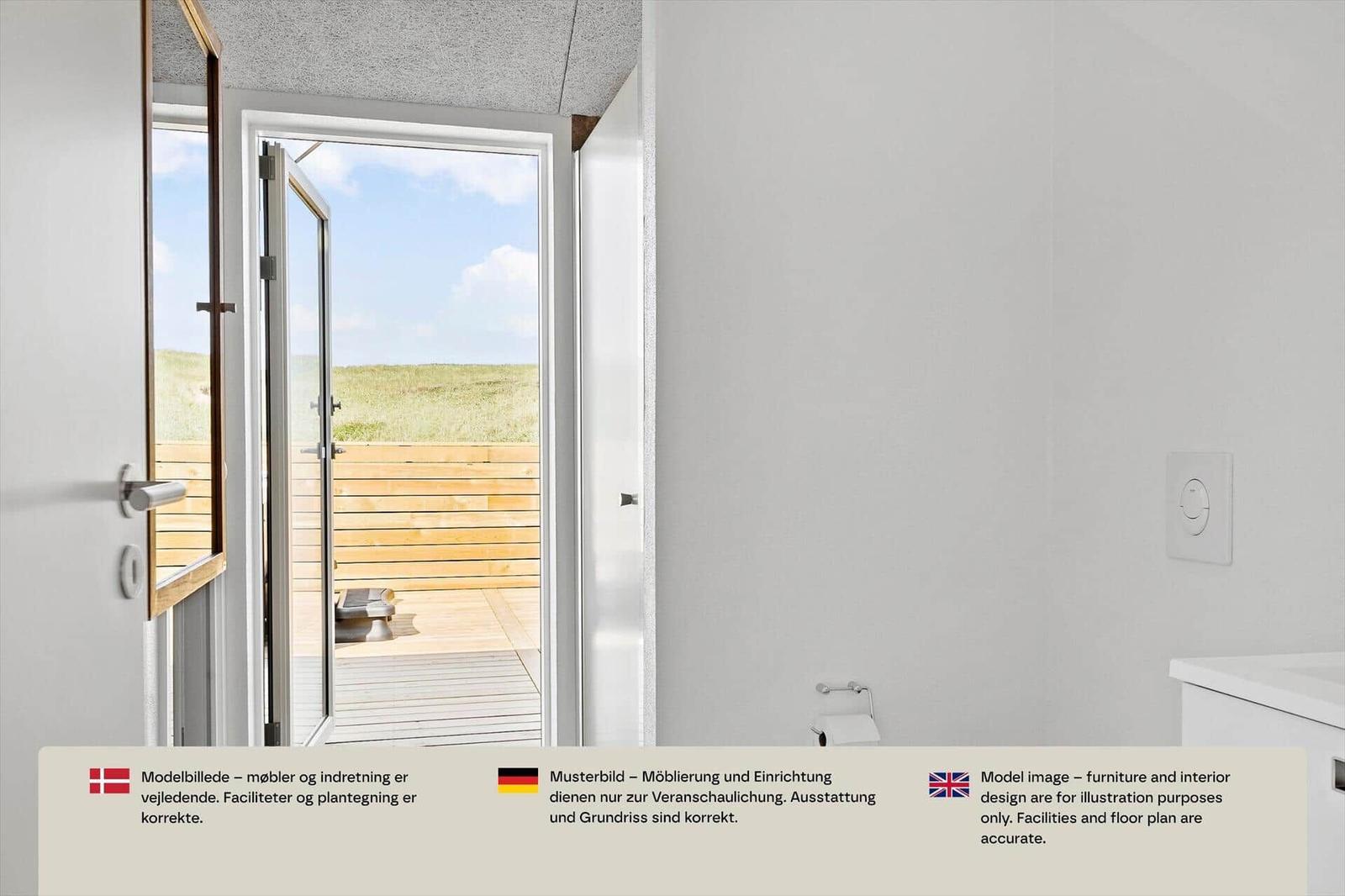 Bad mit Spiegel und Blick durch offene Glastür auf Holzterrasse und Dünen.