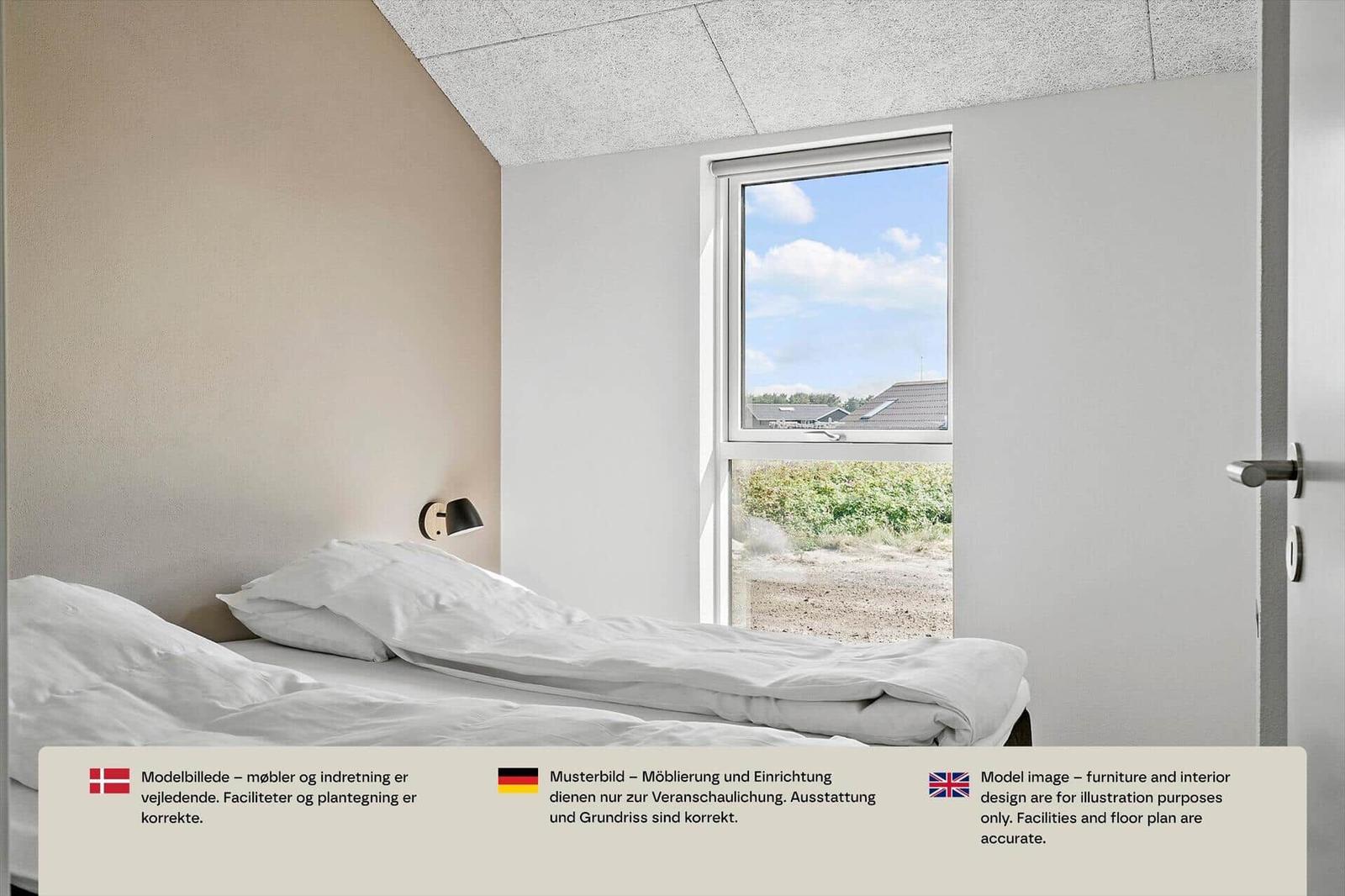 Schlafzimmer mit weißem Bett, beiger Wand, Wandlampe und Fenster nach draußen.