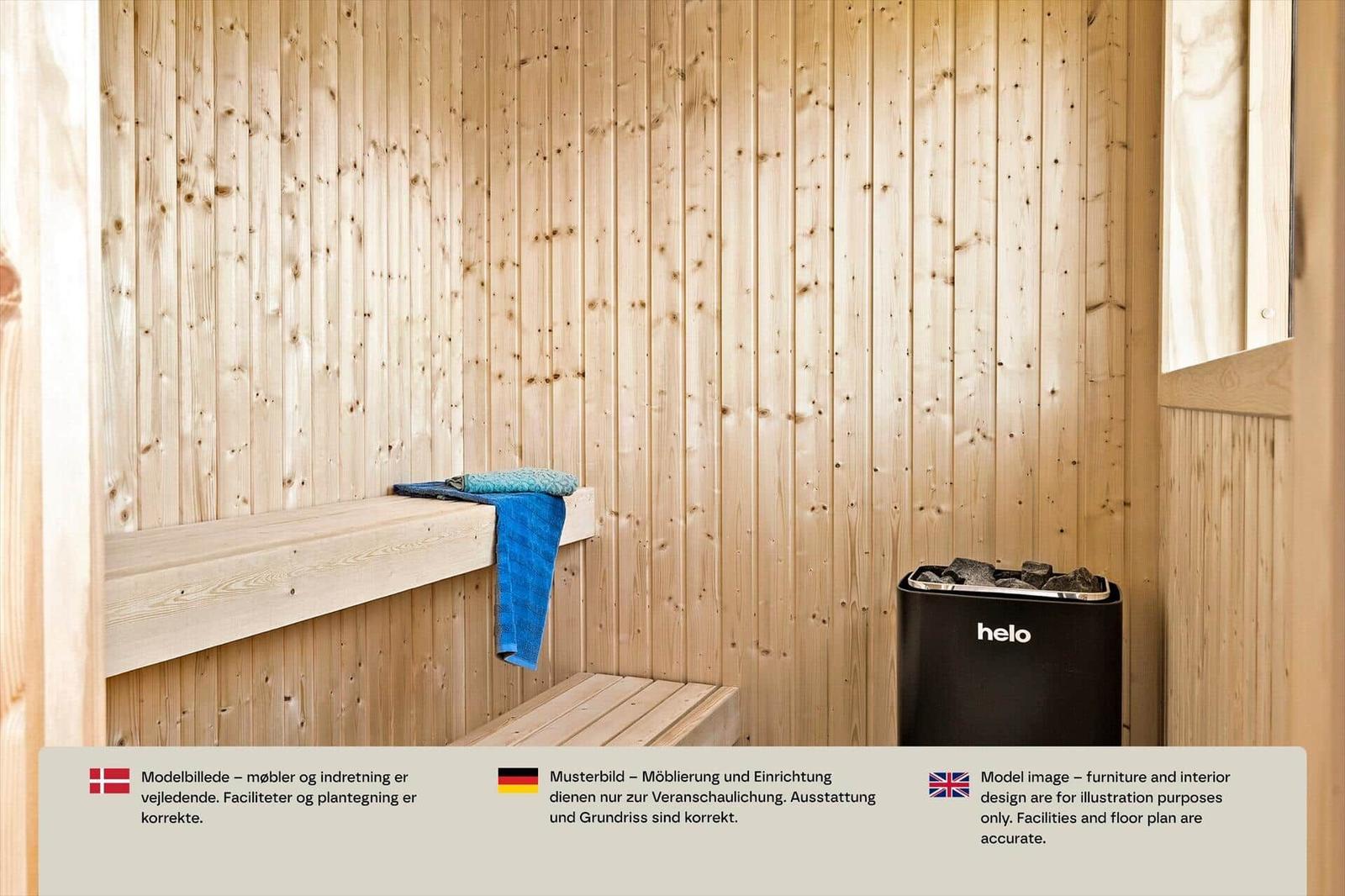 Sauna mit hellen Holzbänken, blauen Handtüchern und schwarzem Ofen mit Steinen.