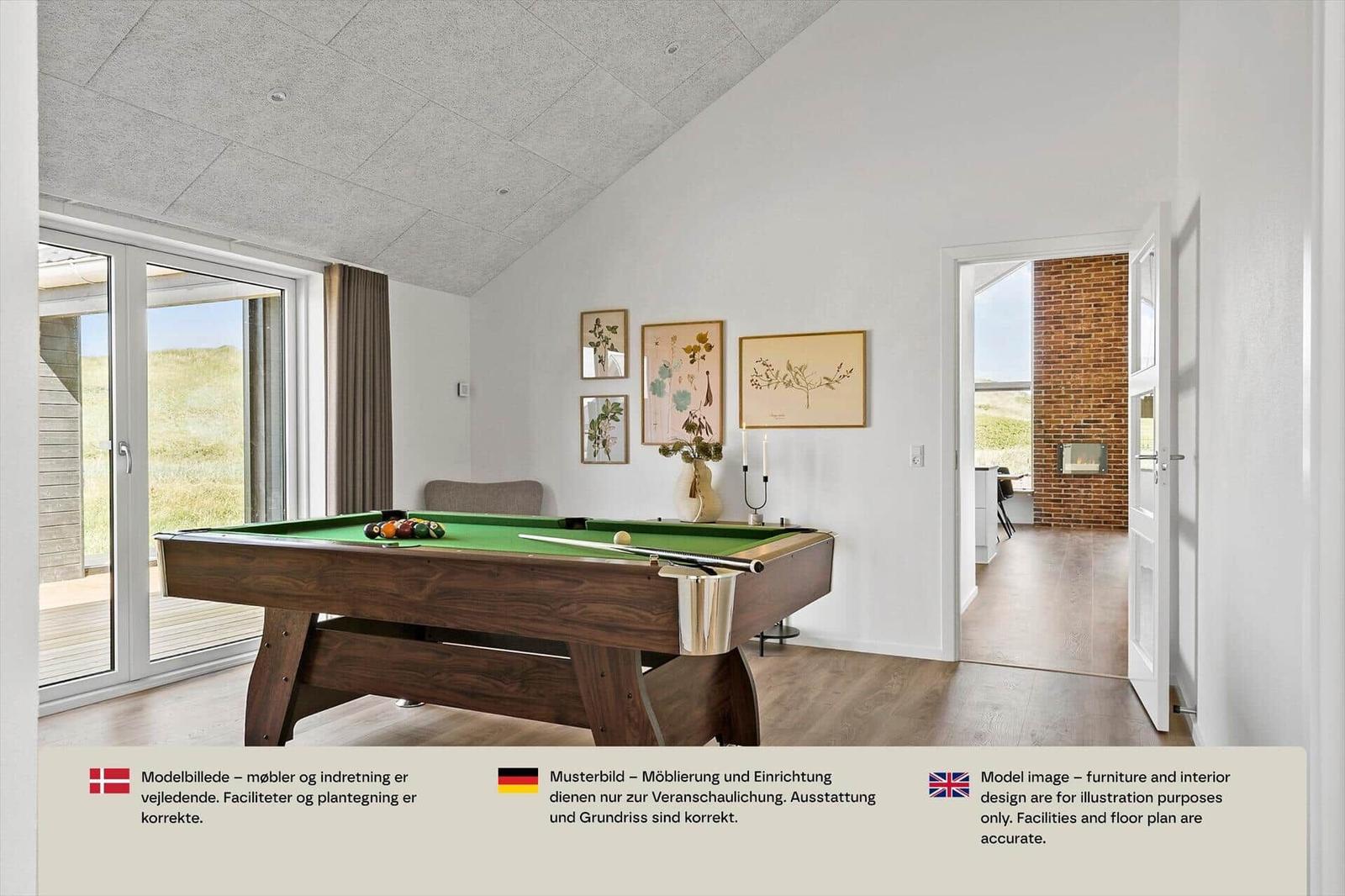 Billardtisch mit grünem Tuch in hellem Raum mit Terrassentür und Holzboden.