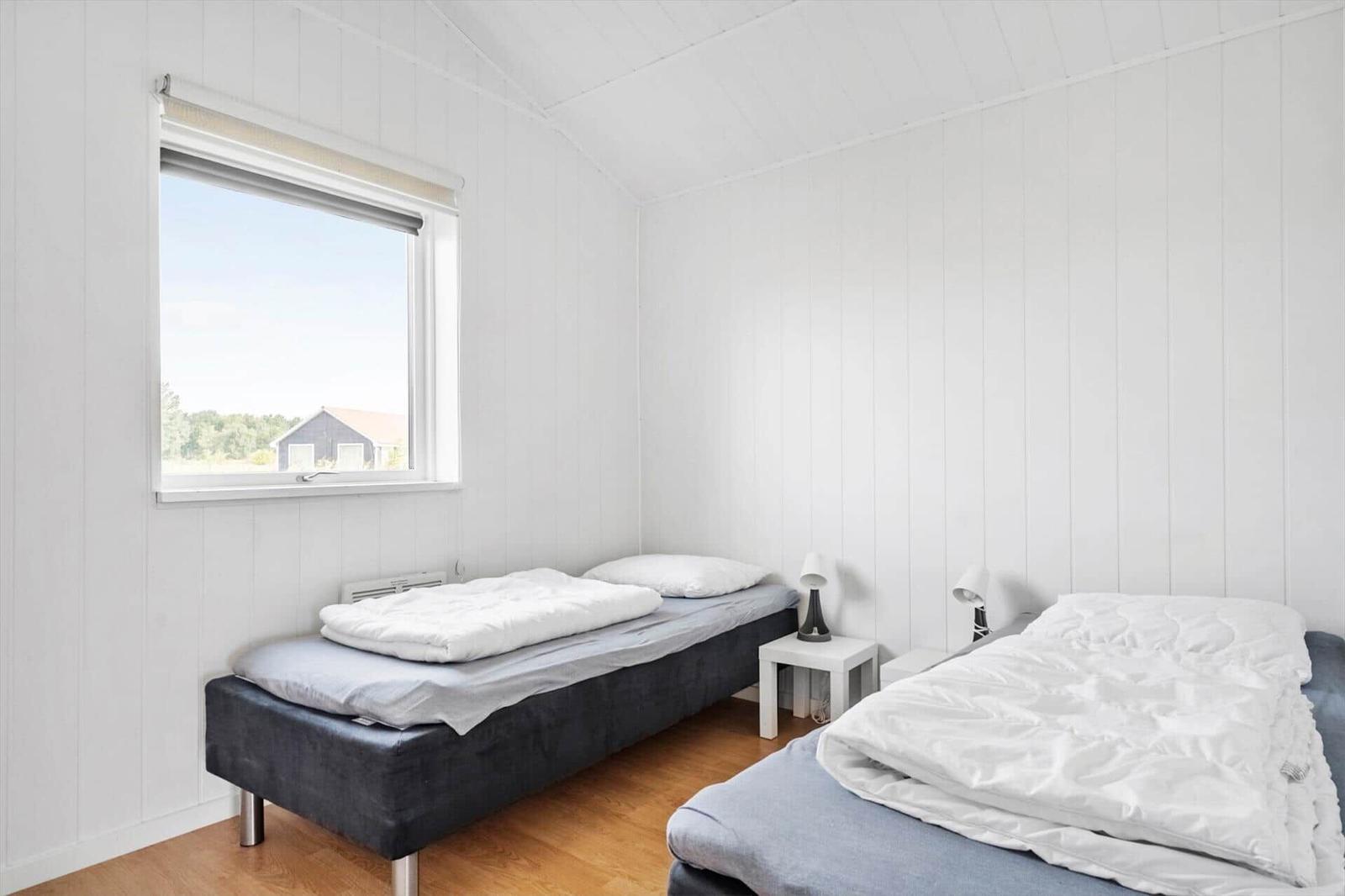 Bedroom with two single beds side by side, nightstand and window.