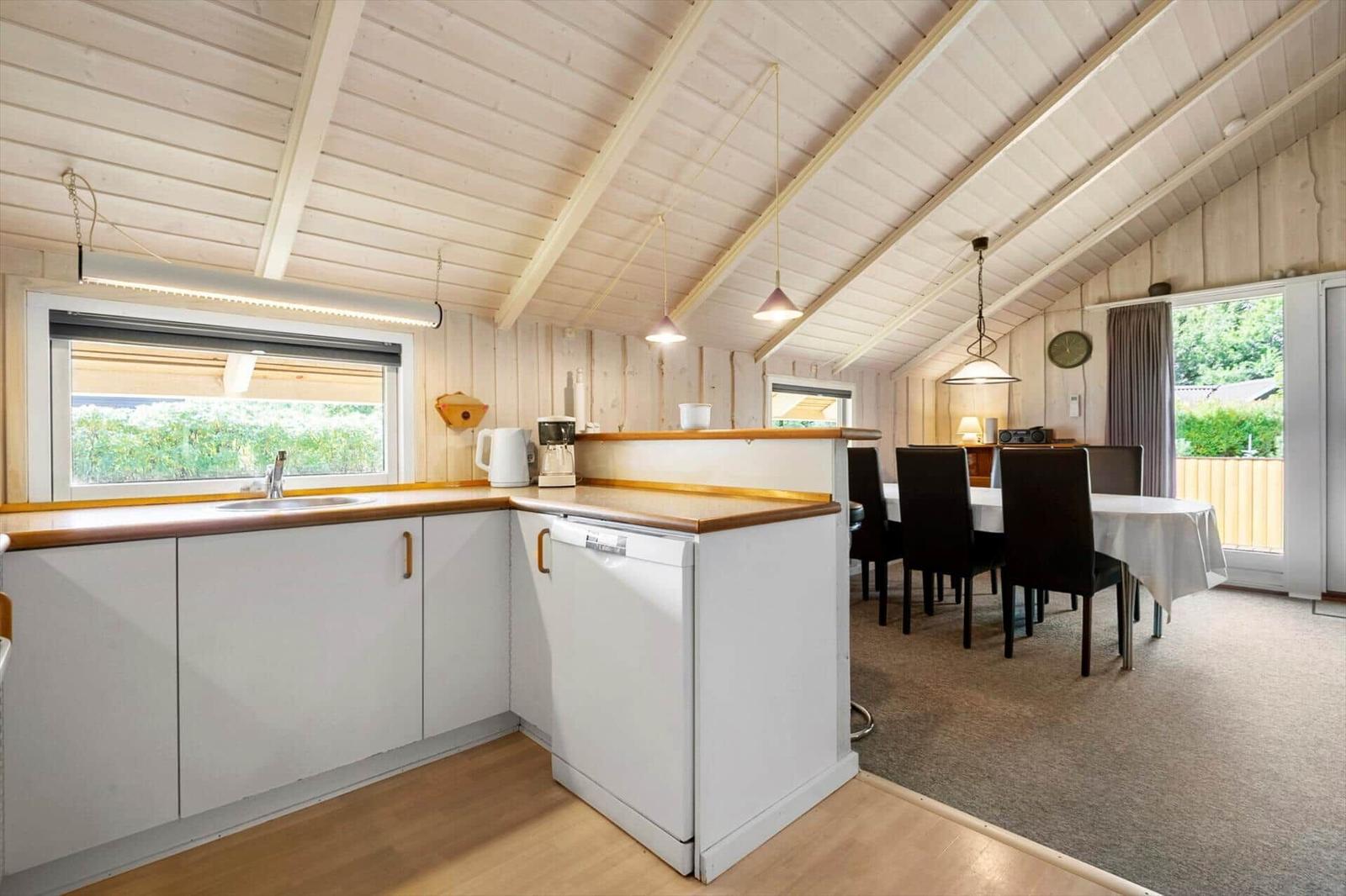 Open kitchen with dining table, six black chairs and glass door to the terrace.