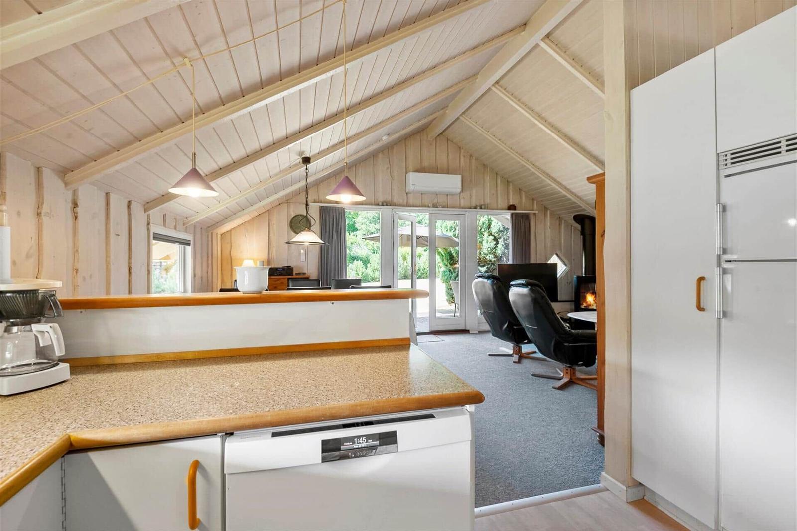 Kitchen with view into living area, wood stove and black armchairs.