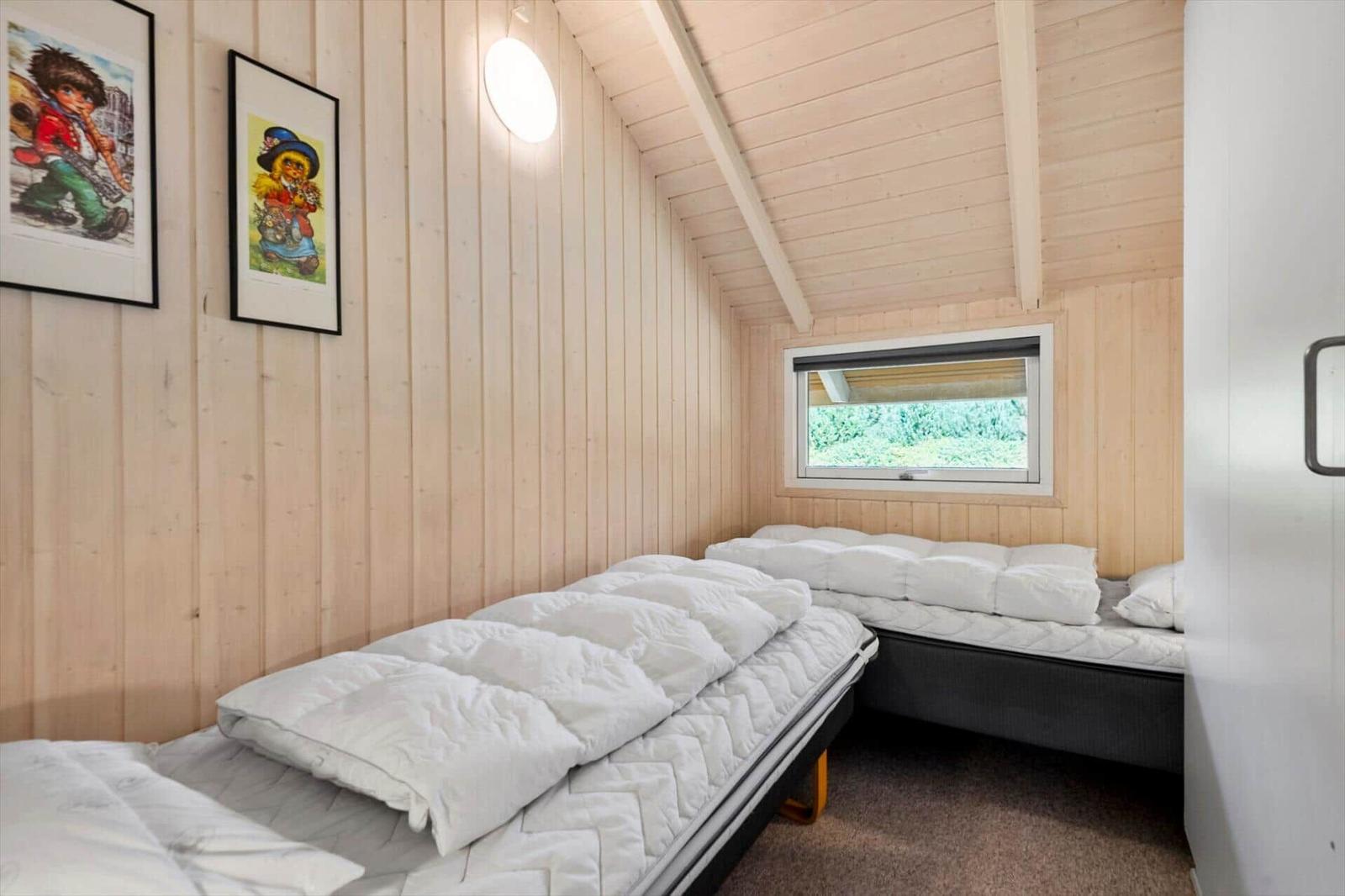 Bedroom with two single beds, wood paneling and a window with a blind.