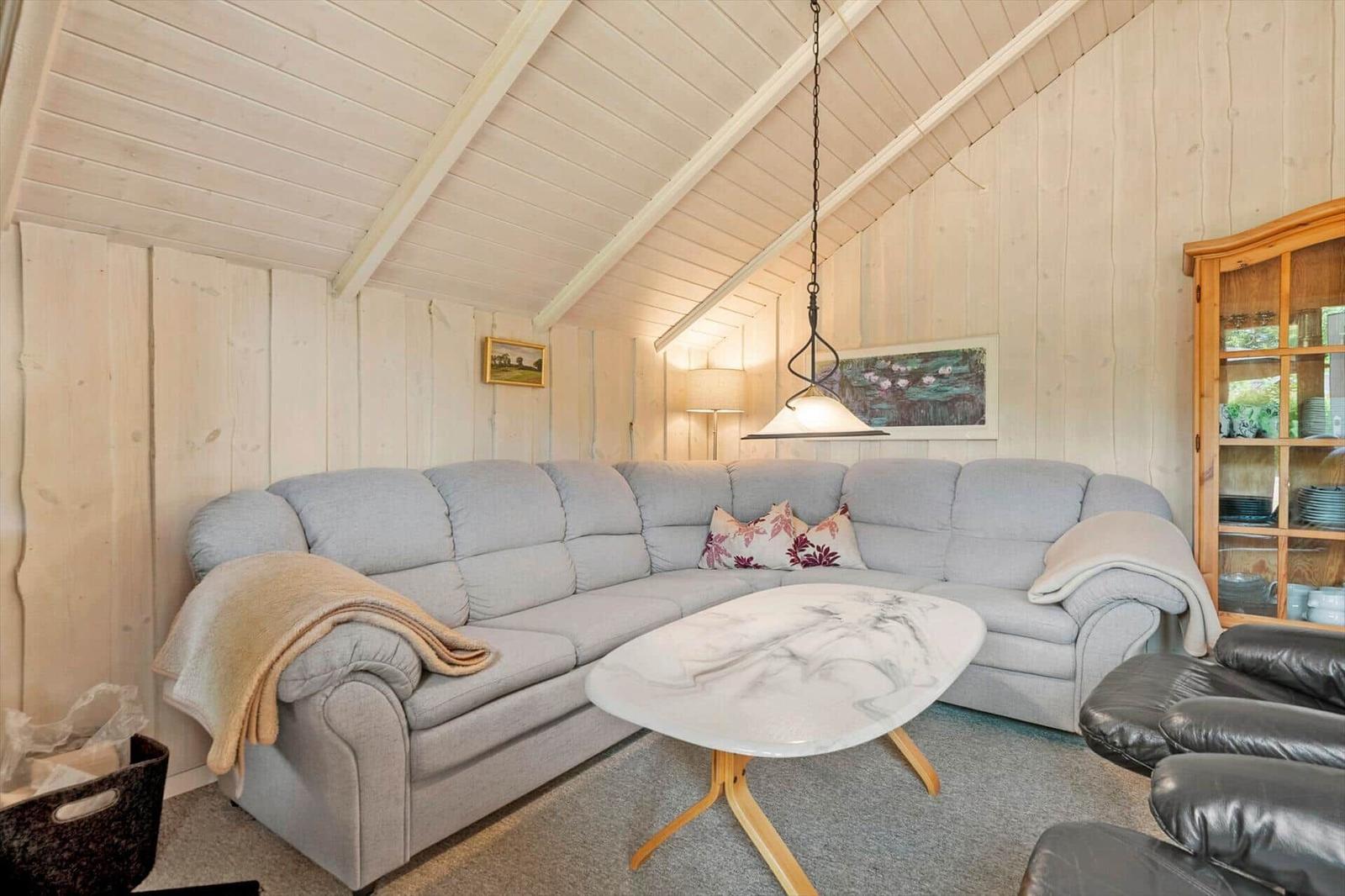 Living area with grey corner sofa, oval coffee table and wooden display cabinet.