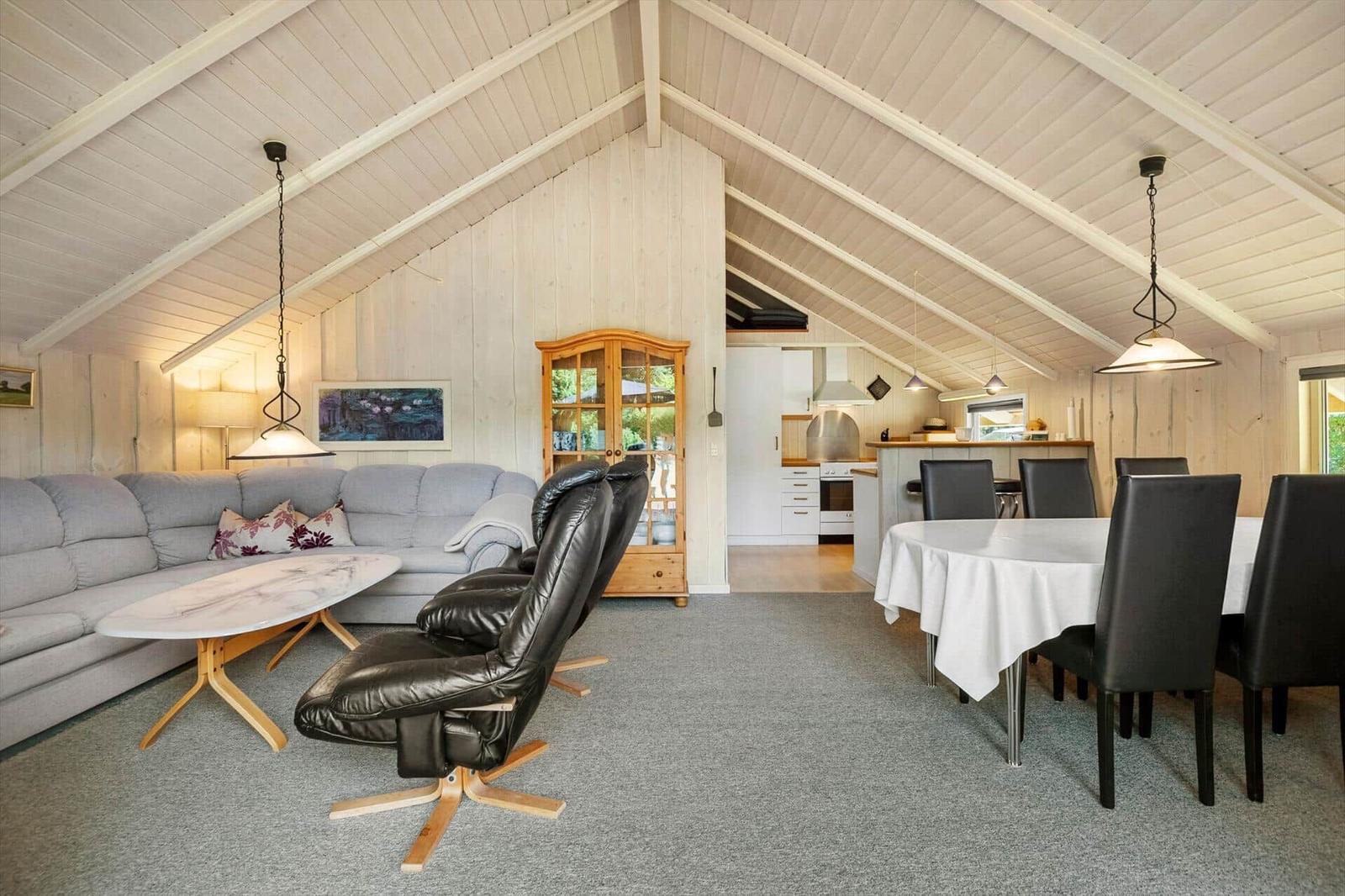 Open living and dining area with sofa, armchairs and dining table under a gable.