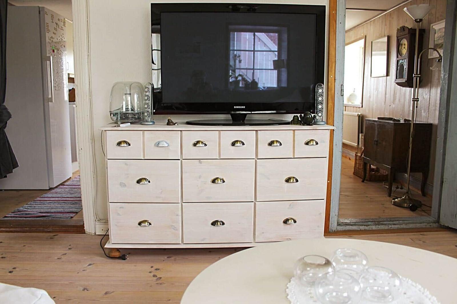 Kleine Küche mit Kühlschrank, Schränken und Bildern an der Wand.