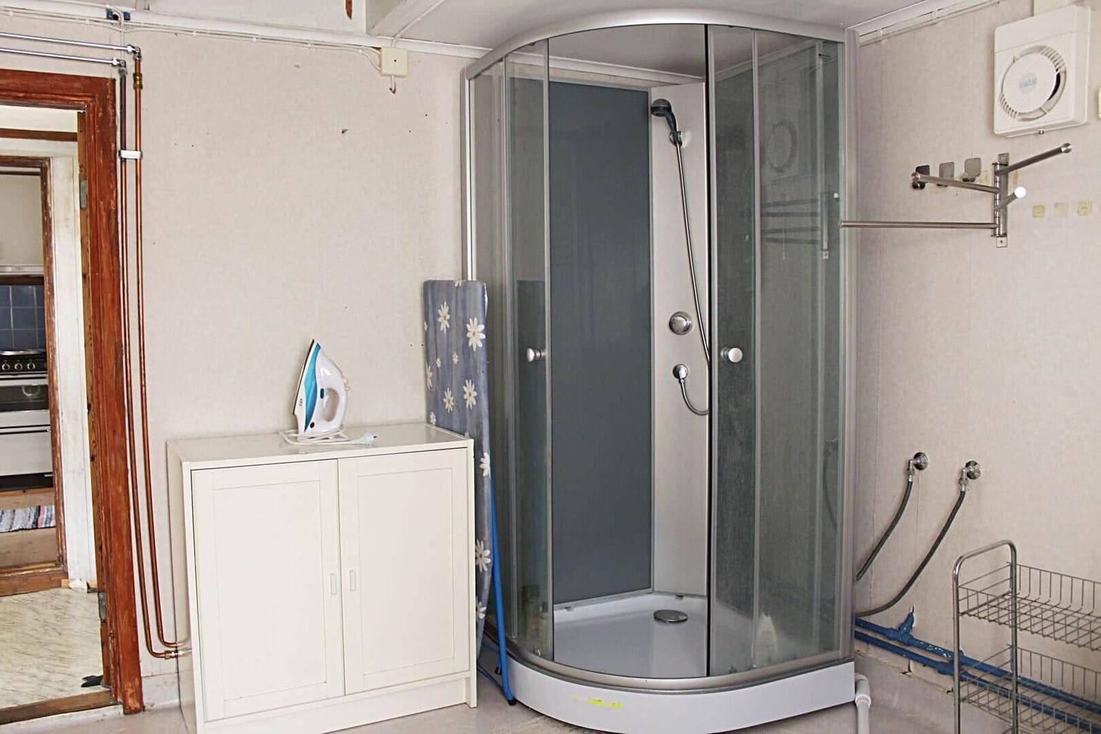 Badezimmer mit Waschmaschine, Spiegel und Toilette. Fliesenboden und Beistellkabinett.