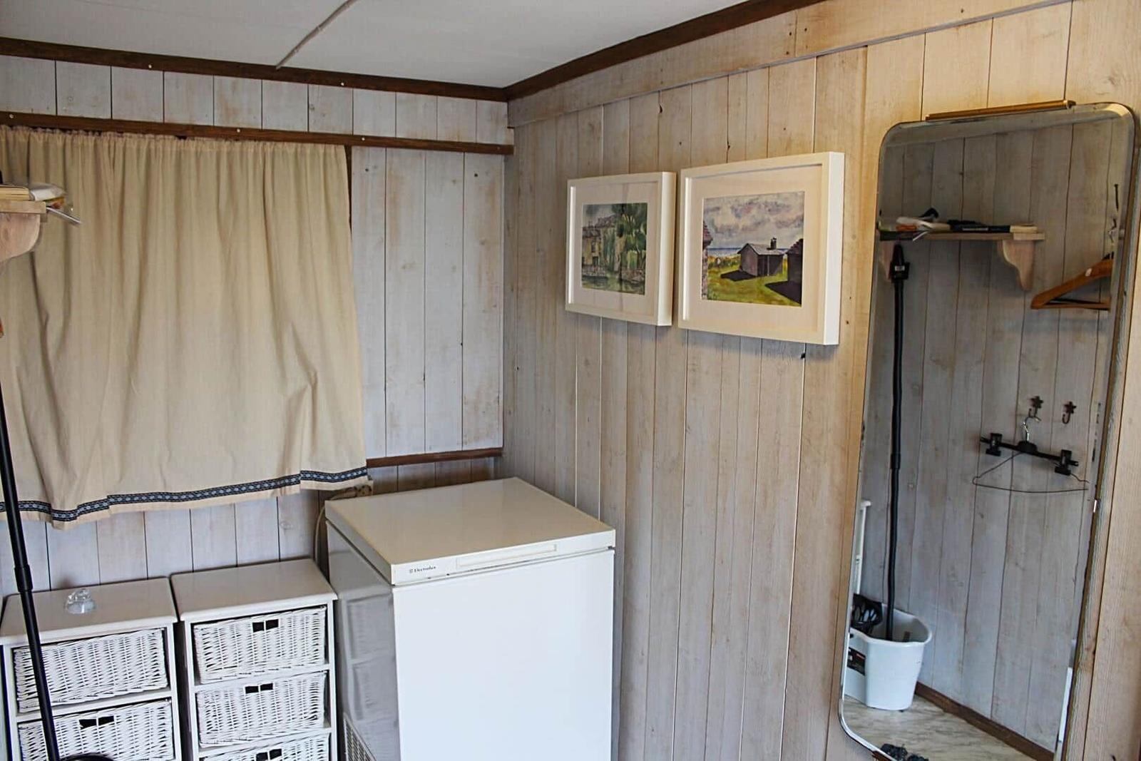 Dachgeschosszimmer mit Holzboden, Kleiderständer und Korb. Sicht auf Treppenhaus und Wand.