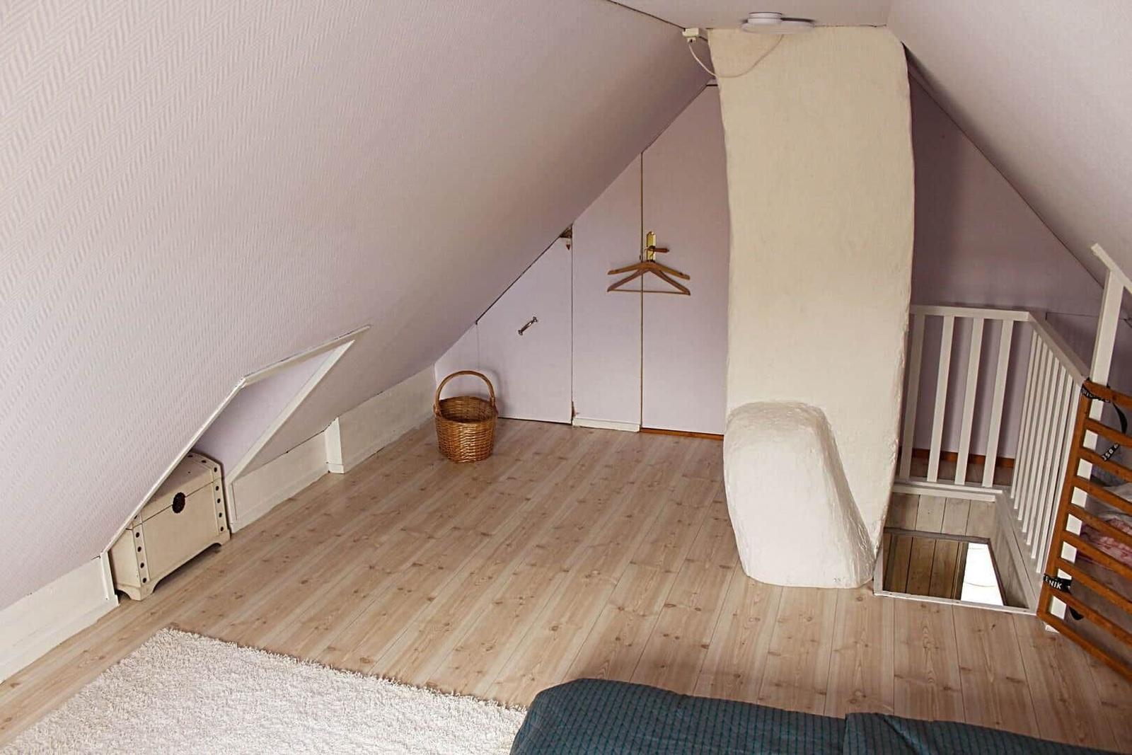 Zwei Betten in einem Dachzimmer mit Fenster und hellen Wänden.