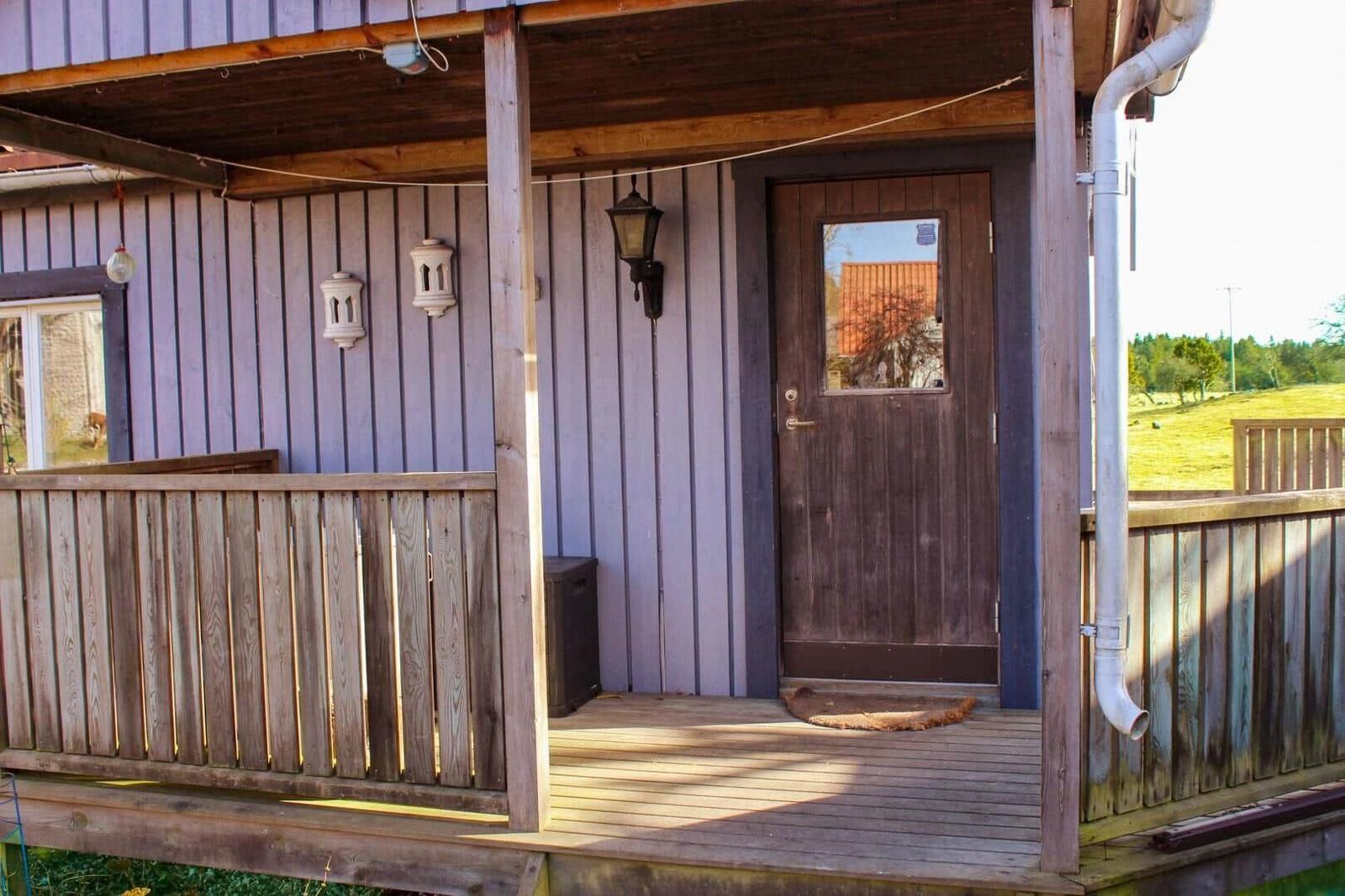 Zimmer mit zwei Betten, Holzboden und Trennwand. Fenster und Pflanze sichtbar.
