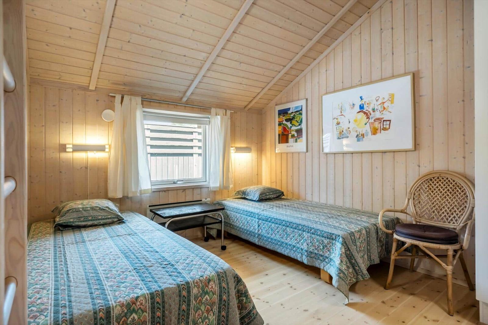 Schlafzimmer mit Bett, Schränken und Fenster. Holzwände und -decke.