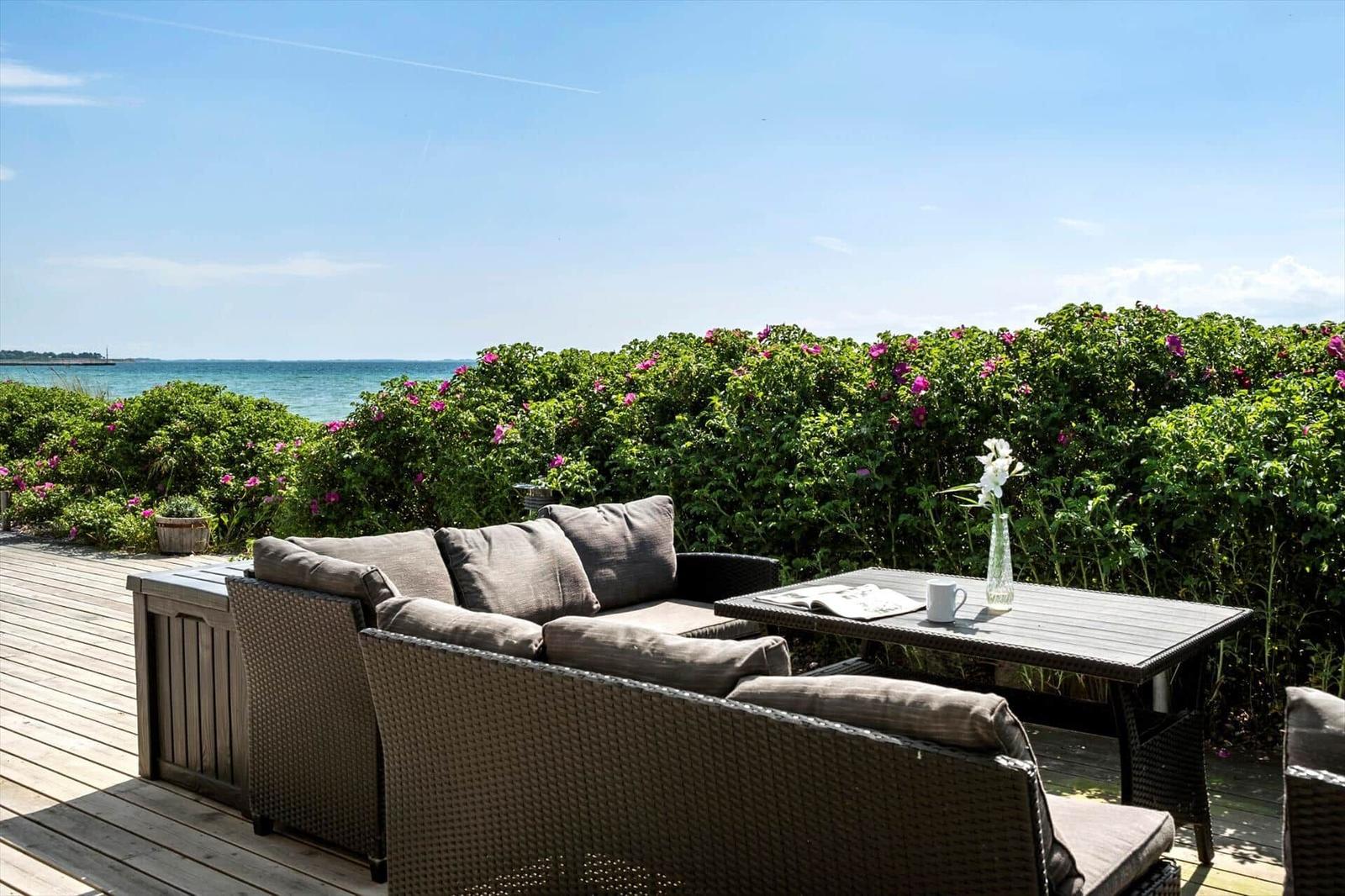 Terrasse mit Liegestühlen, Tisch und Stühlen, Haus mit Grill und Auto.