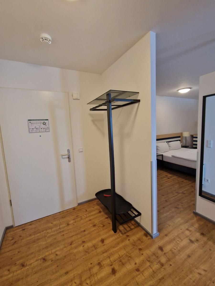 Flur mit Garderobe und Blick auf Doppelbett mit gestreiftem Kopfteil.