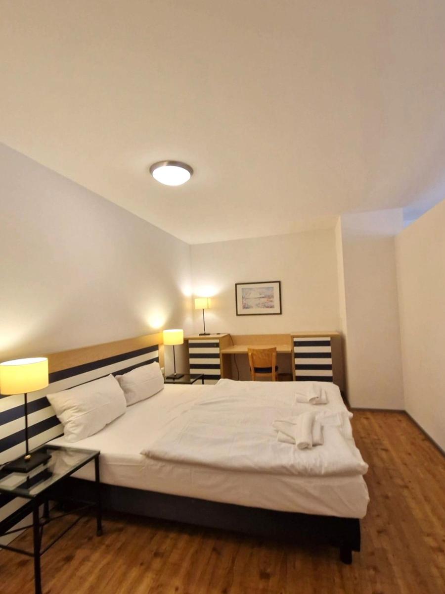 Schlafzimmer mit Doppelbett, gestreiftem Kopfteil und Schreibtisch.