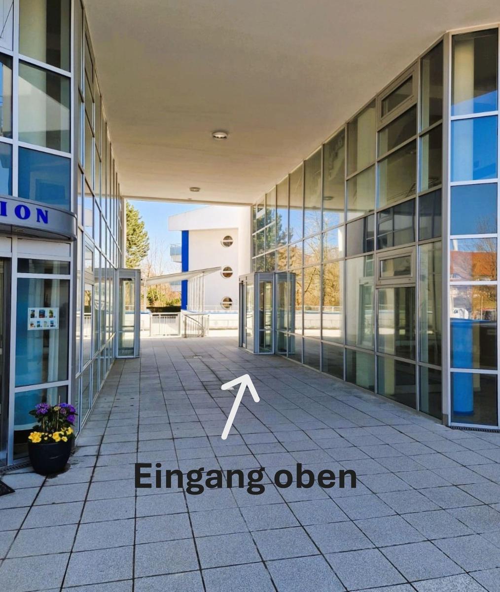 Gepflasterter Glasdurchgang mit Pfeil und Hinweis Eingang oben.