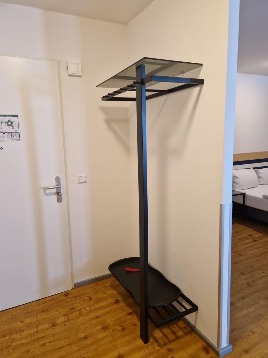 Schwarze Garderobe mit Glasablage und Schuhschale im Flur neben der Tür.