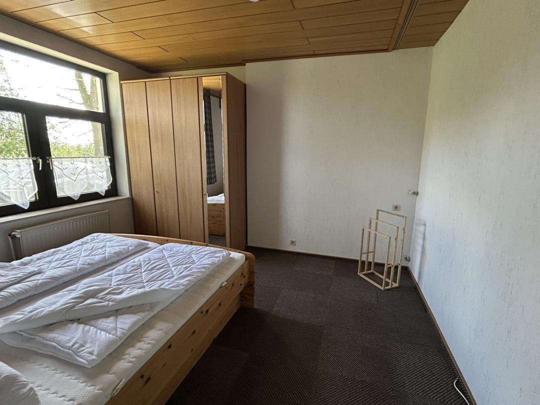 Schlafzimmer mit Holzdoppelbett, Spiegelschrank und Holzpaneeldecke.