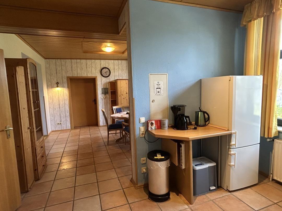 Küchenecke mit Kühlschrank, Kaffeemaschine und Blick zum Essbereich.