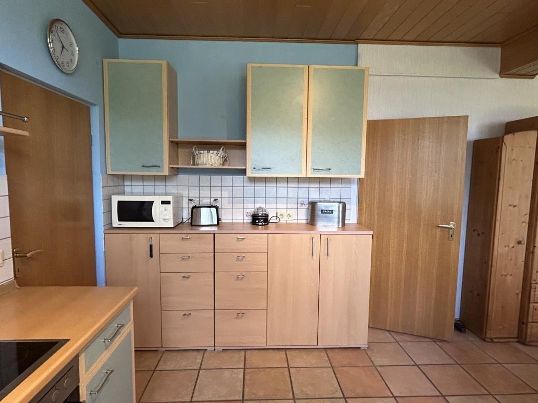 Einbauküche mit Holzfronten, blauer Wand, Mikrowelle und Toaster.