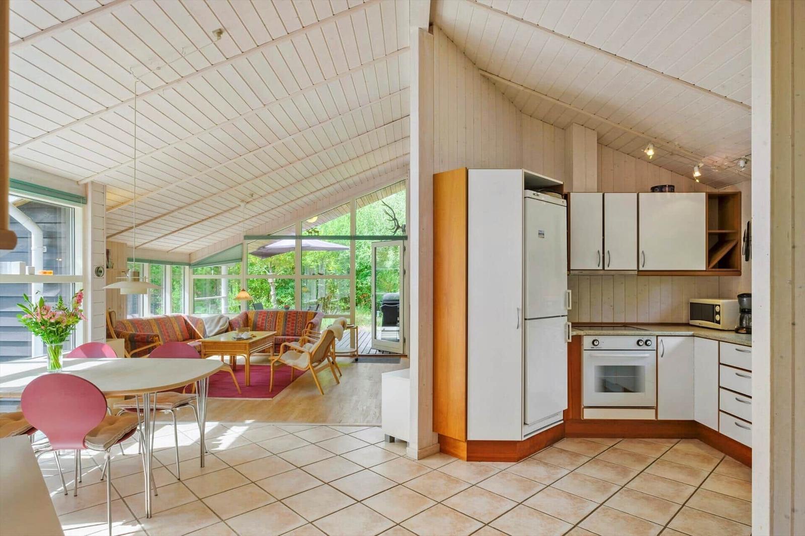 Offener Wohnraum mit Küche, Esstisch, Sofa und großen Fenstern zum Garten.